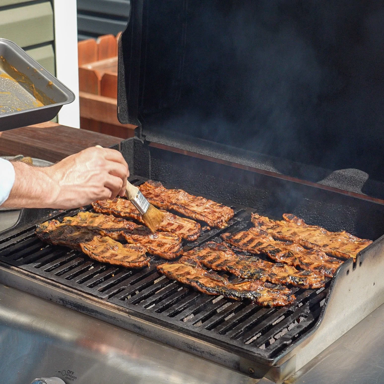 brushing marinade on short ribs on a grill