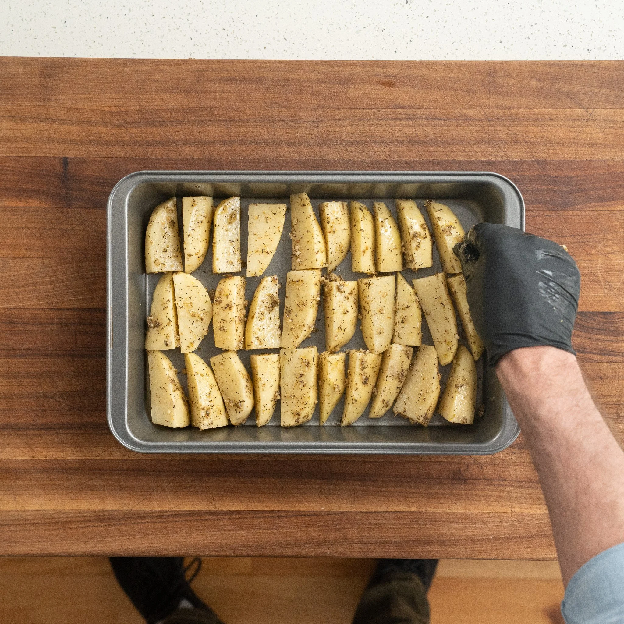 arranging marinated potato wedges in a metal pan
