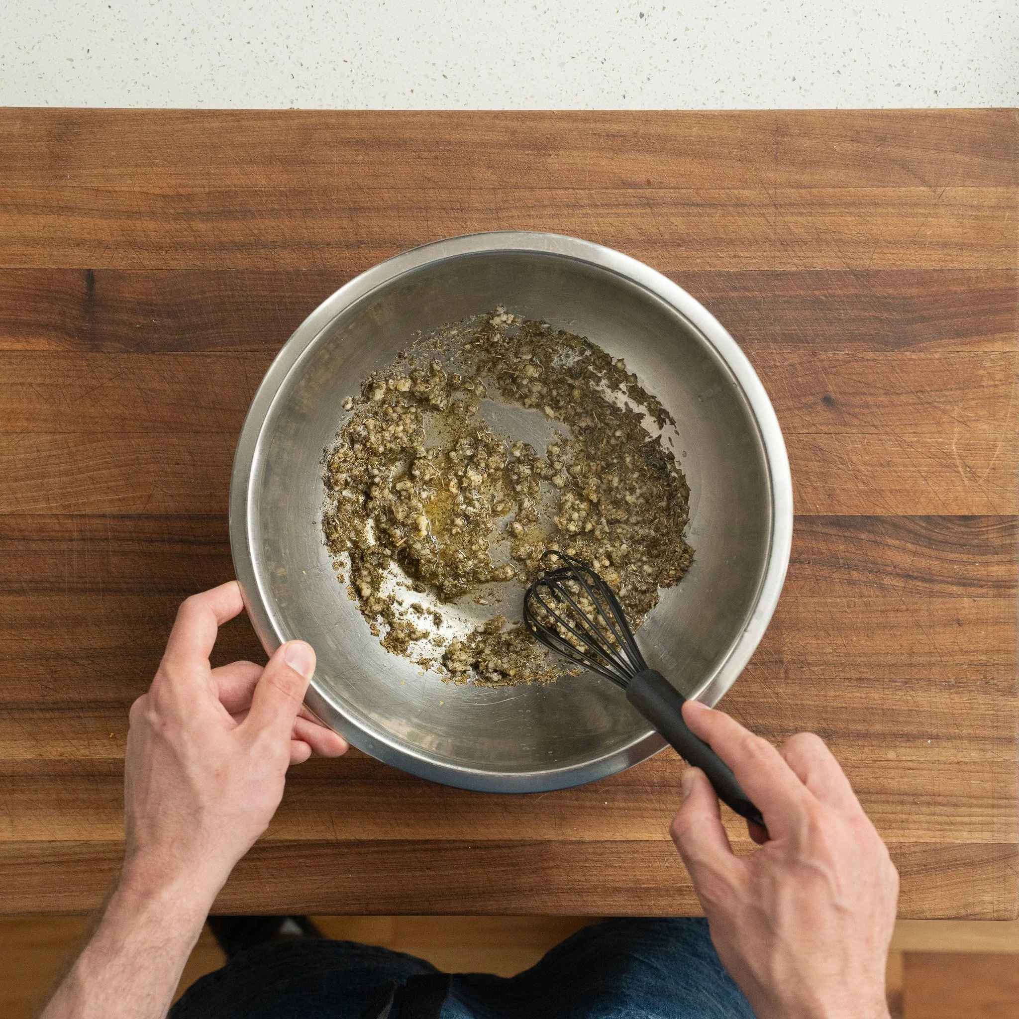whisking together greek marinade ingredients in a metal bowl