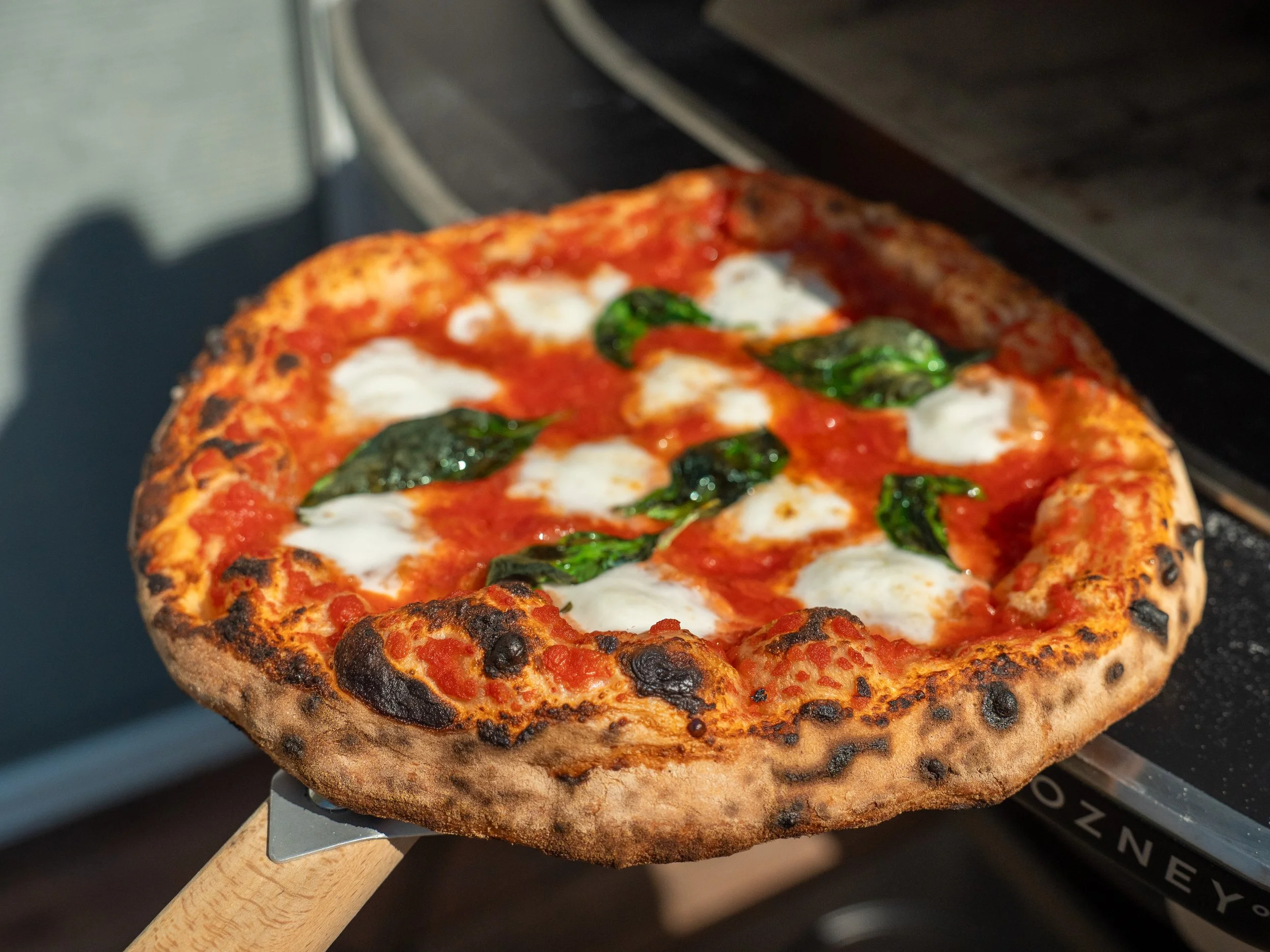 neapolitan pizza being pulled from oven