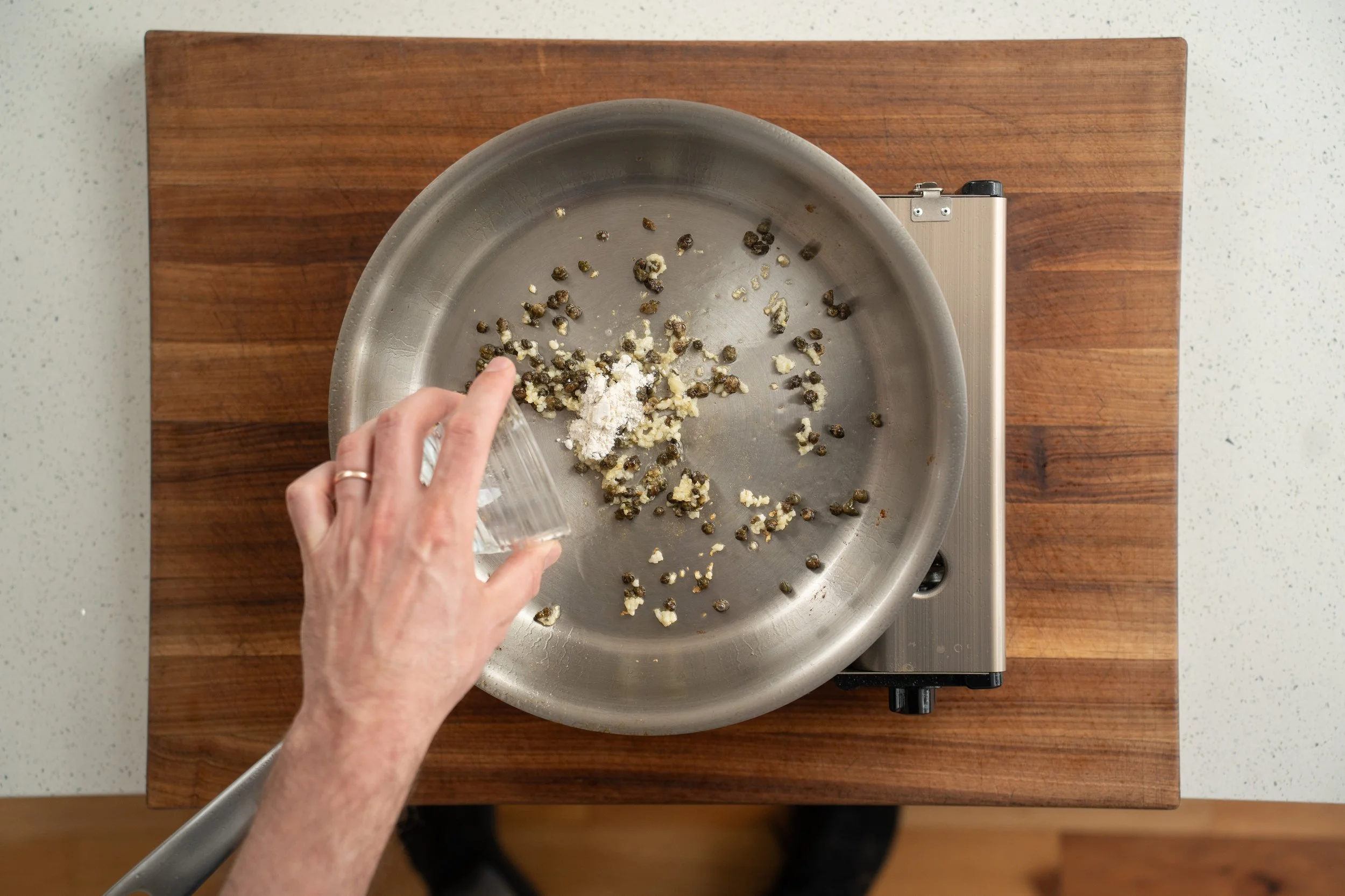 adding flour to capers and garlic