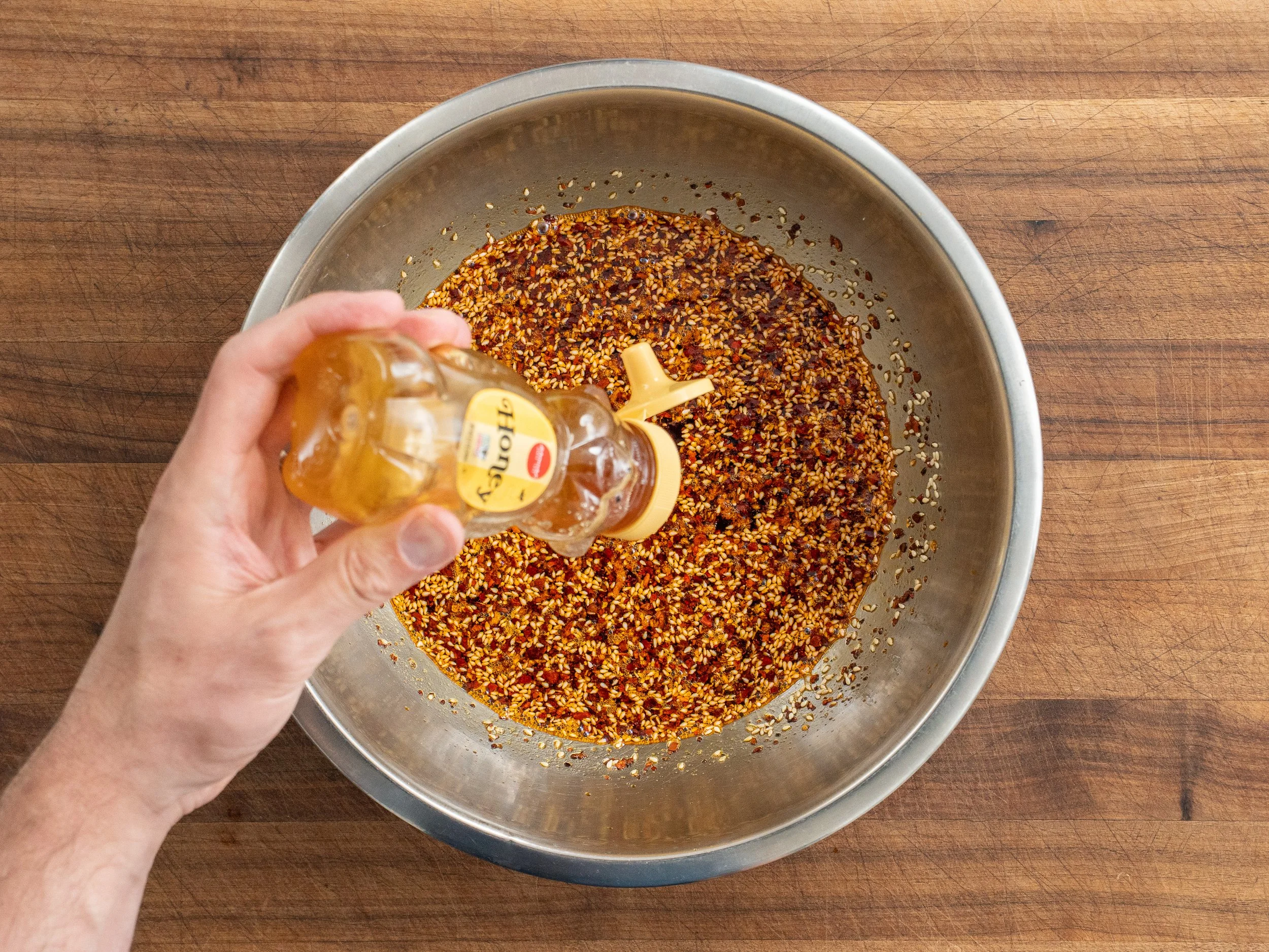 adding honey to a bowl of spices