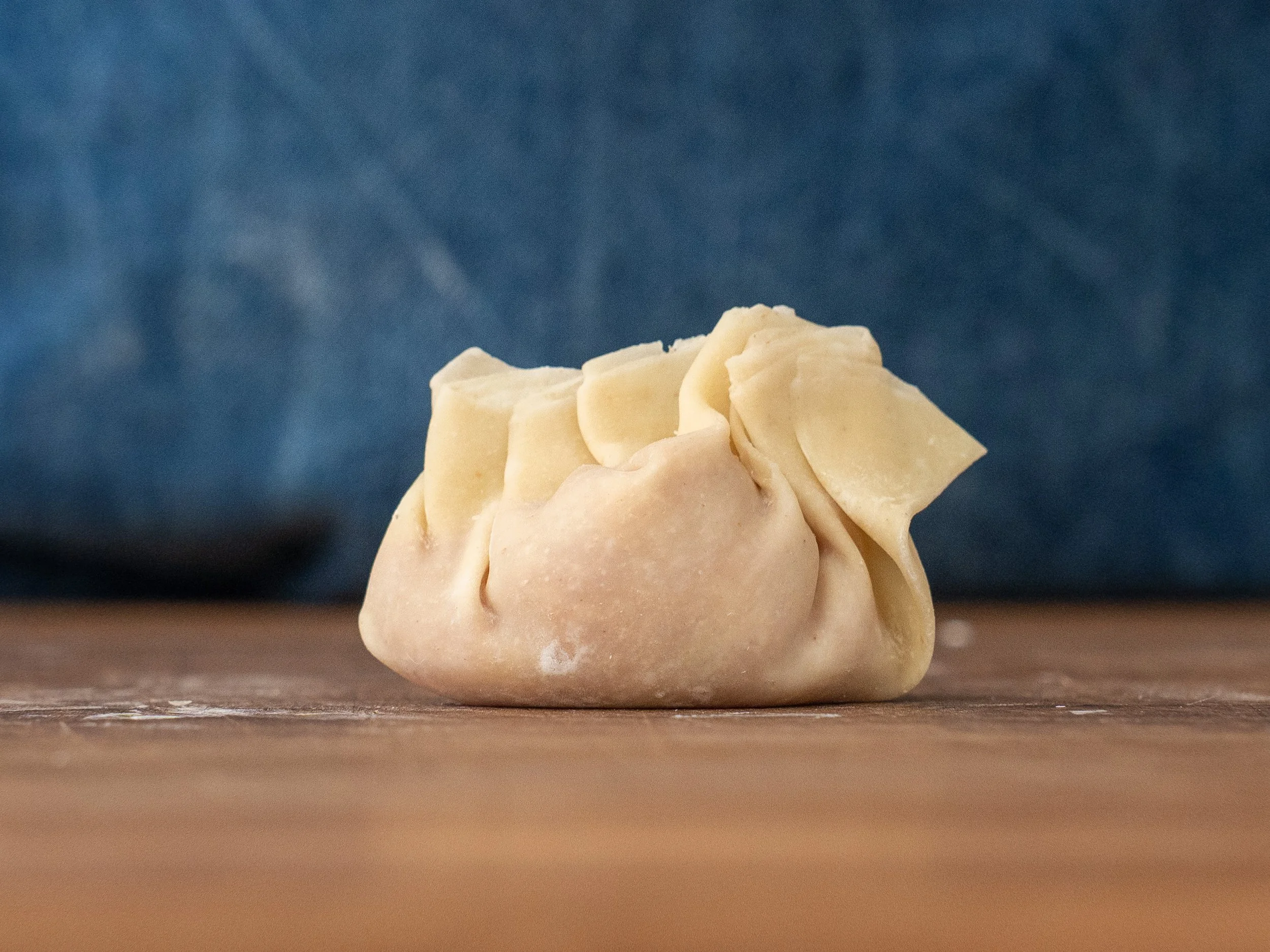 folded beggars purse wonton on wooden cutting board