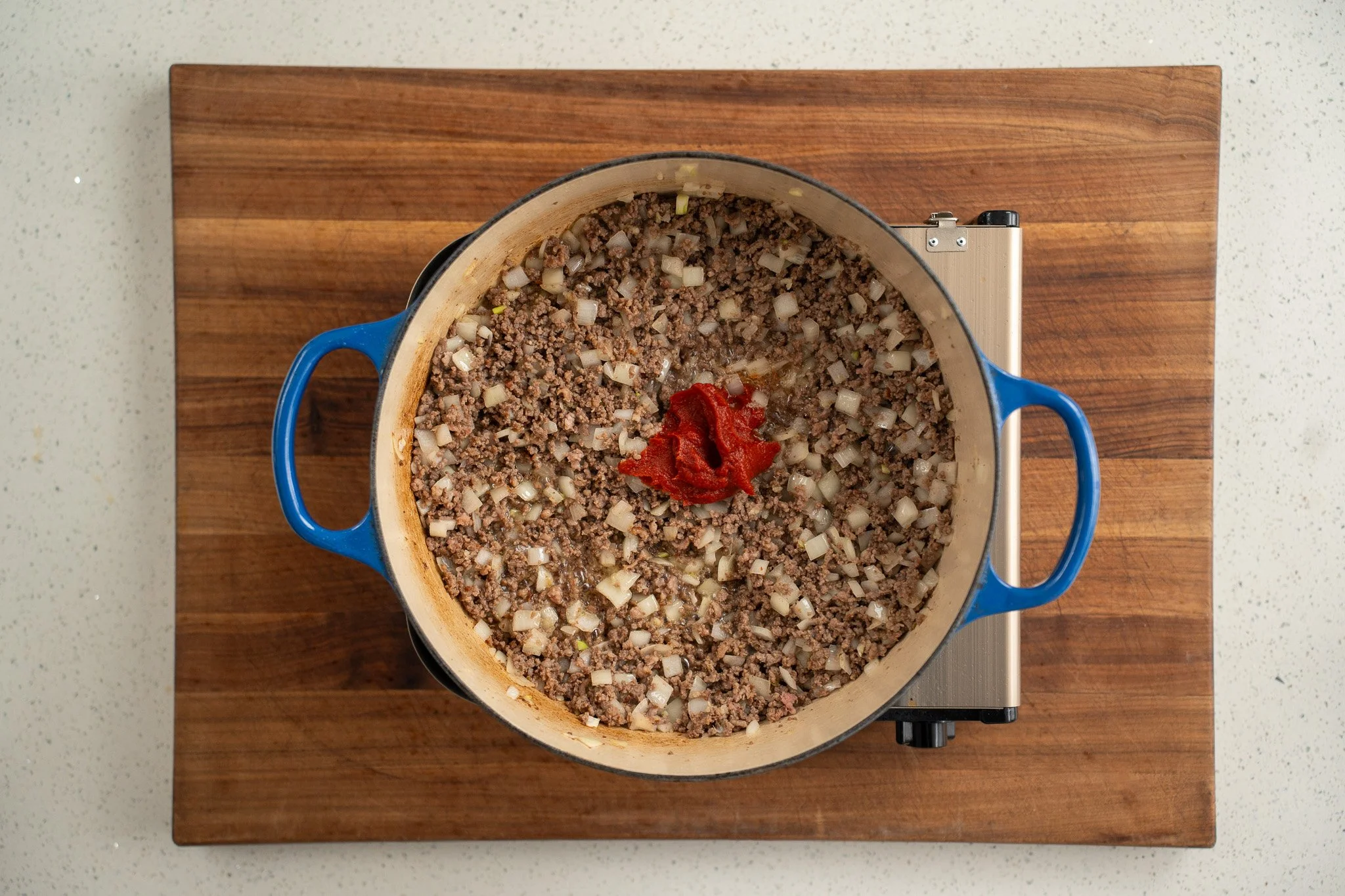 add tomato paste to beef and onions