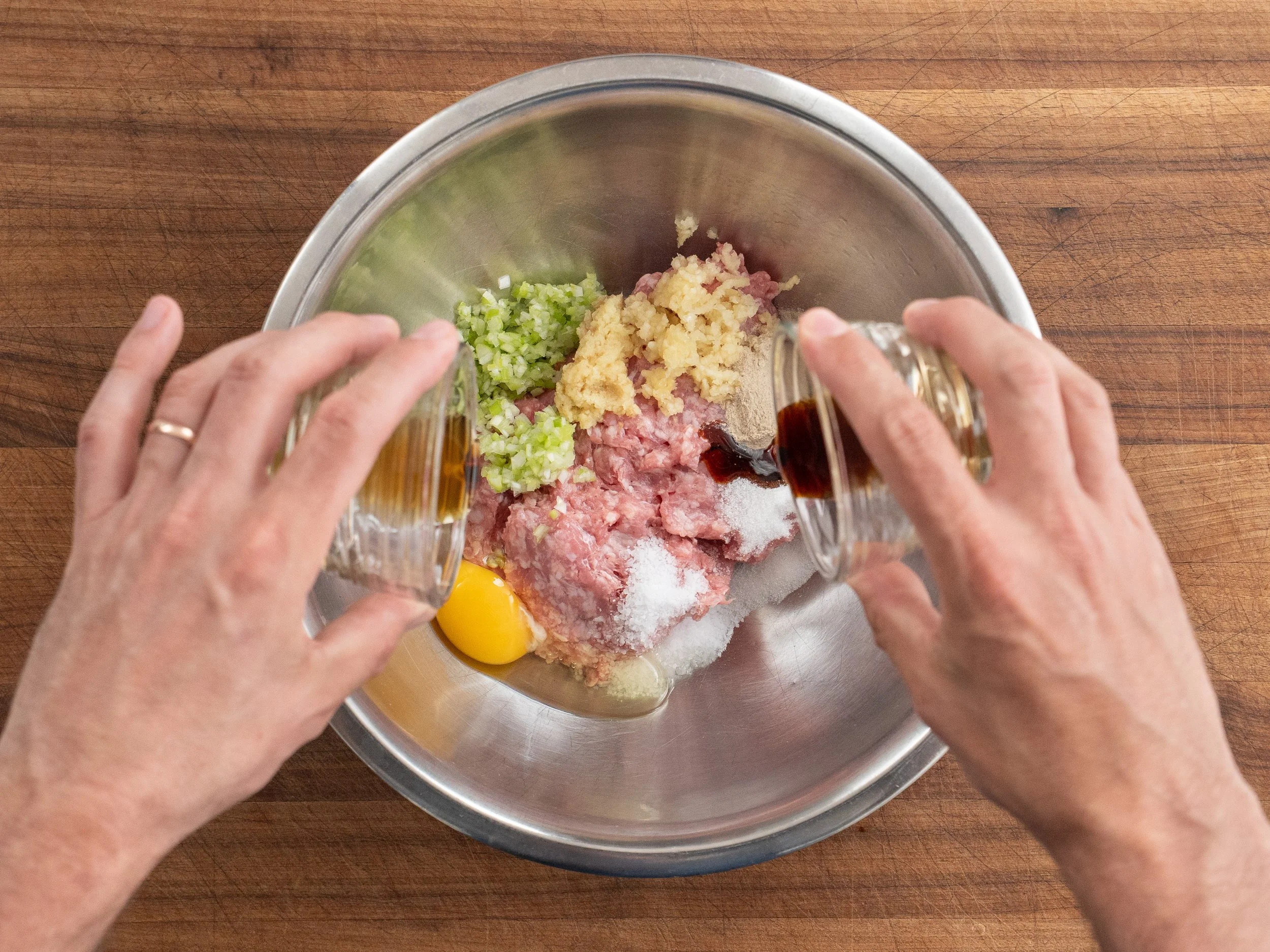 adding brown liquids into a silver bowl