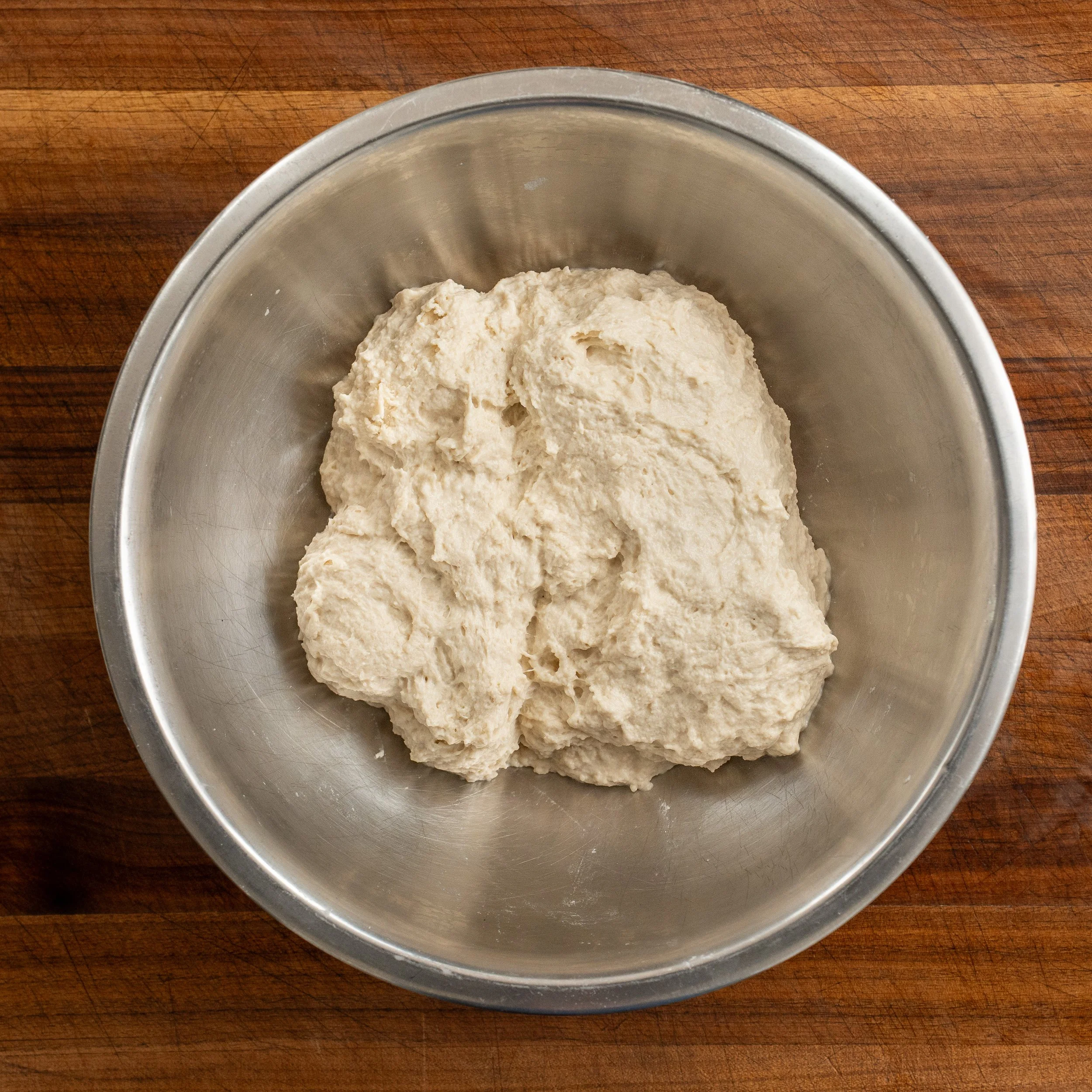shaggy ball of pizza dough in metal bowl