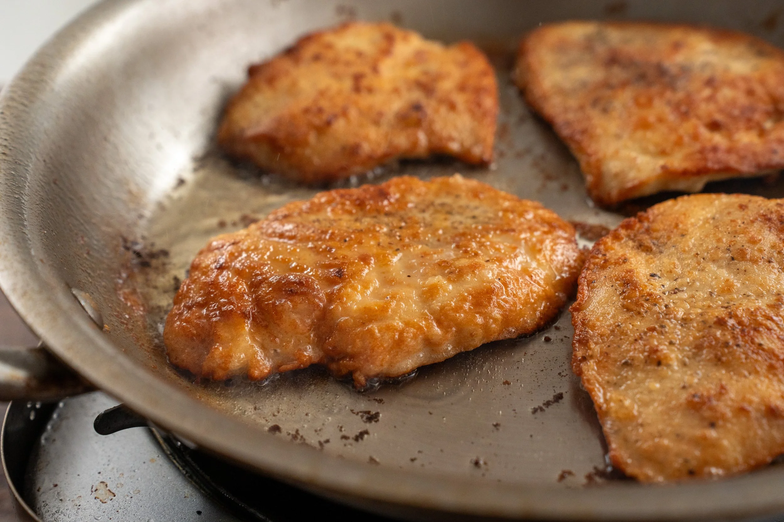browned chicken breast cutlets in a pan