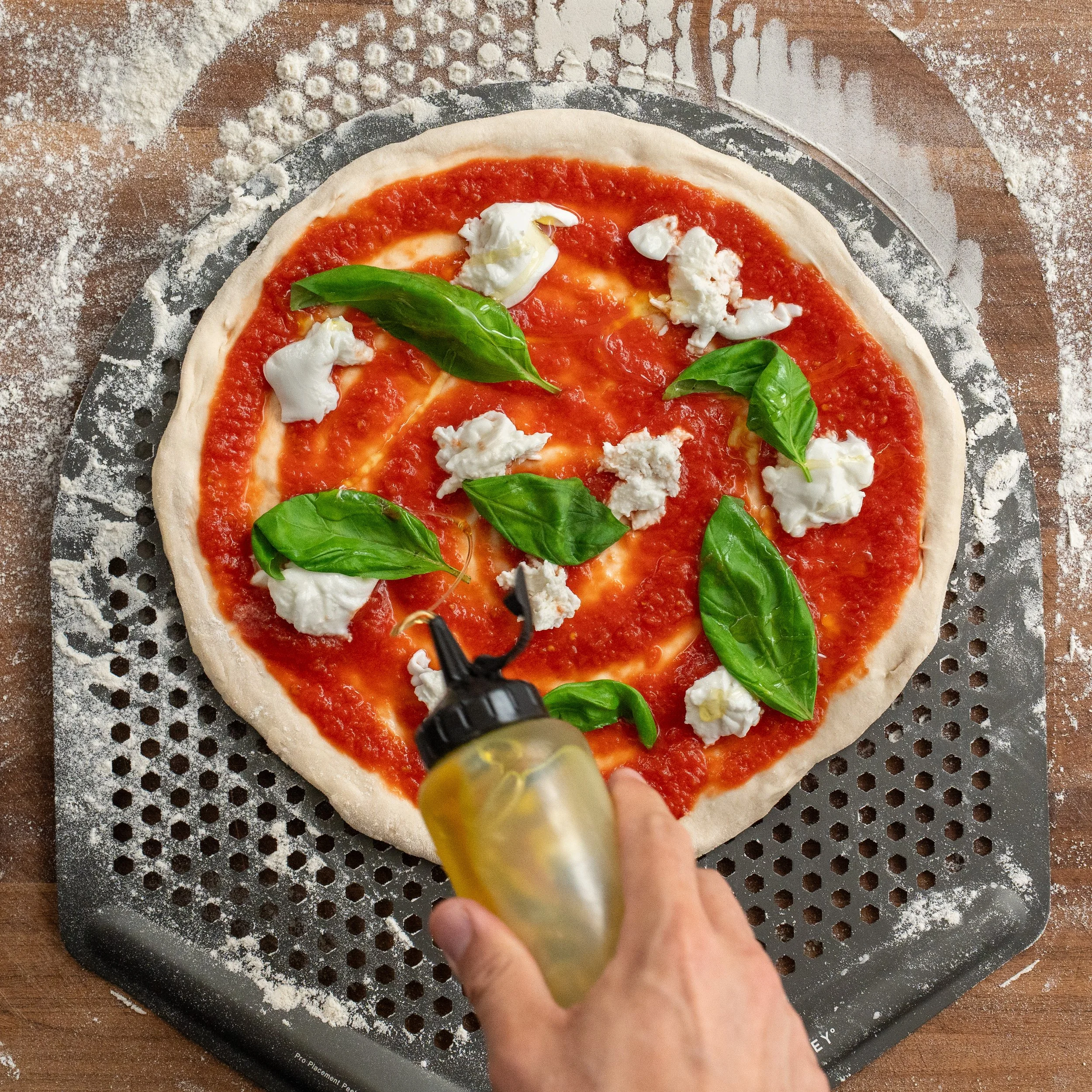 drizzling olive oil onto unbaked Neapolitan pizza