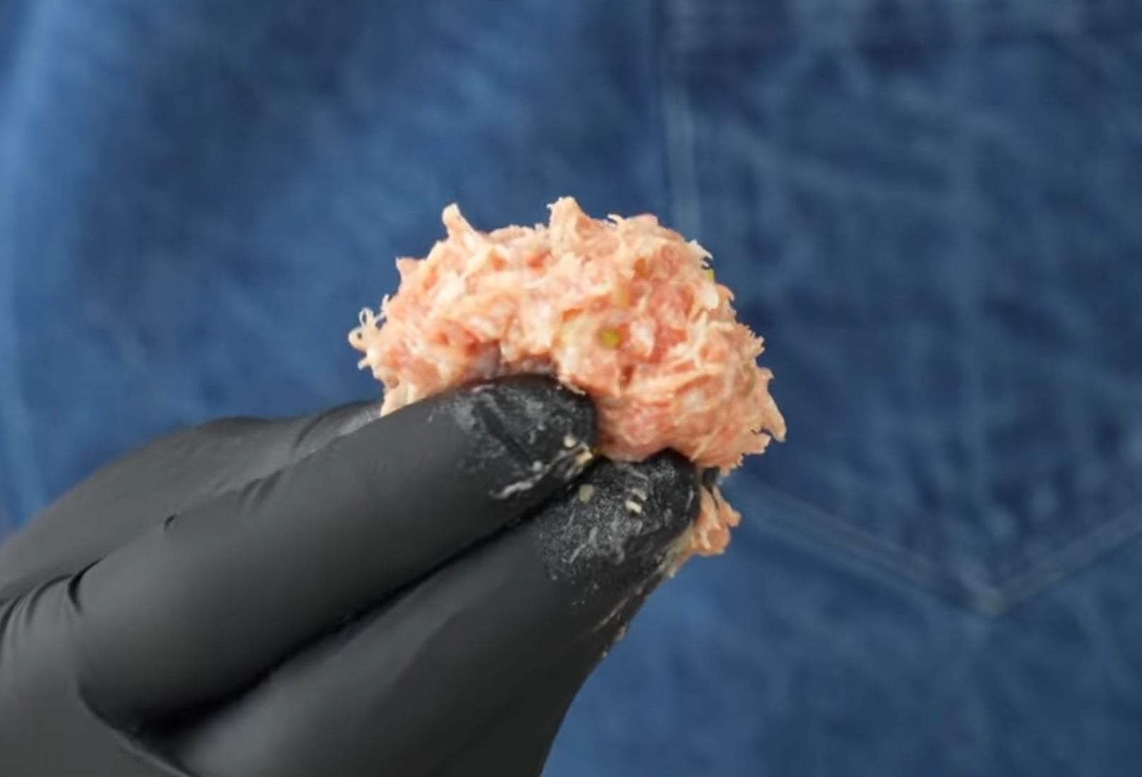 gloved hand holding wonton filling