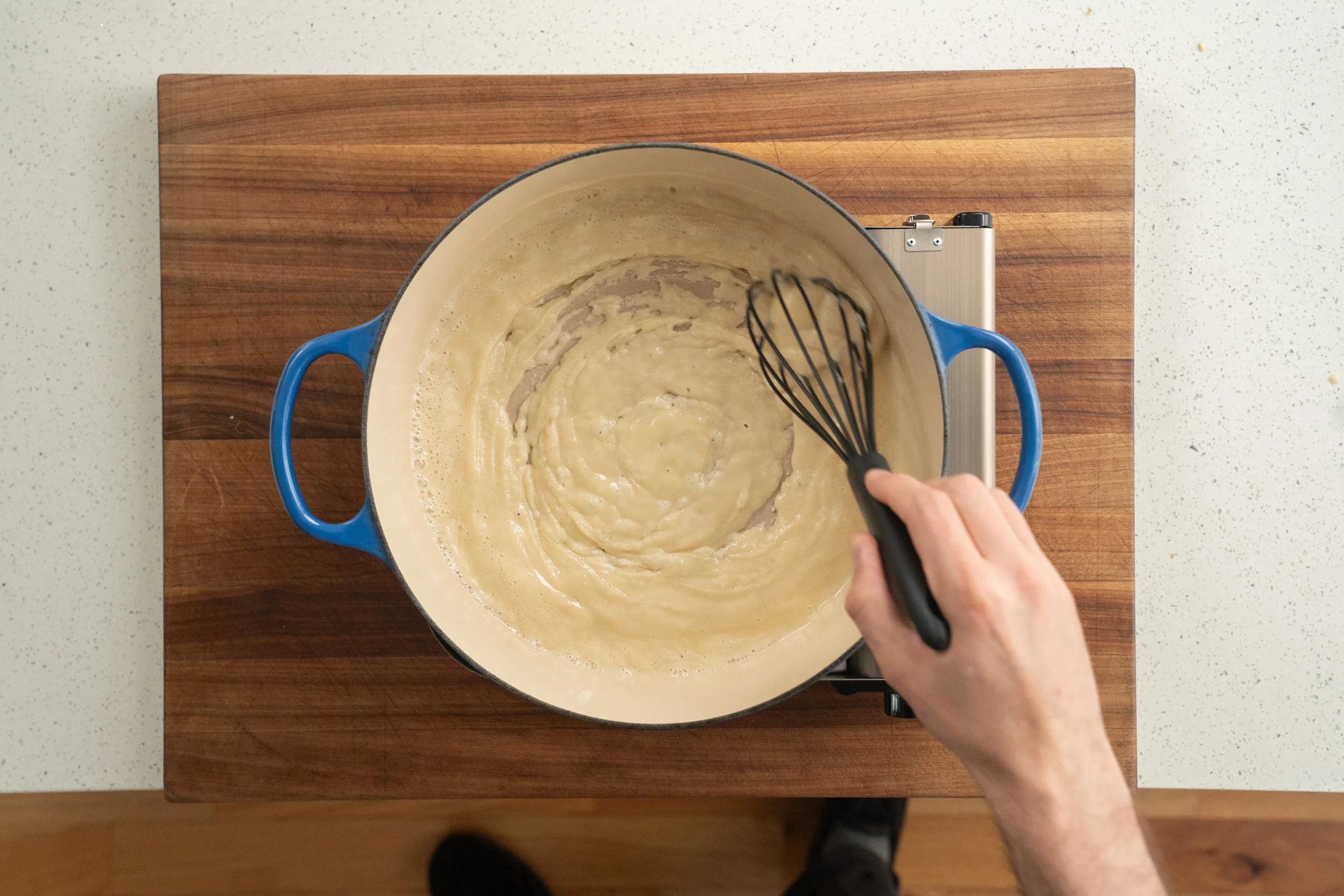 whisking oil and flour together for a roux in blue dutch oven
