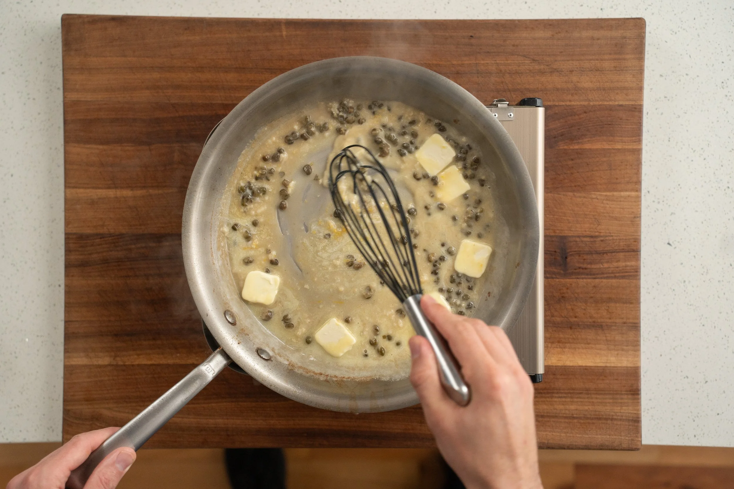 whisking butter into white wine caper sauce