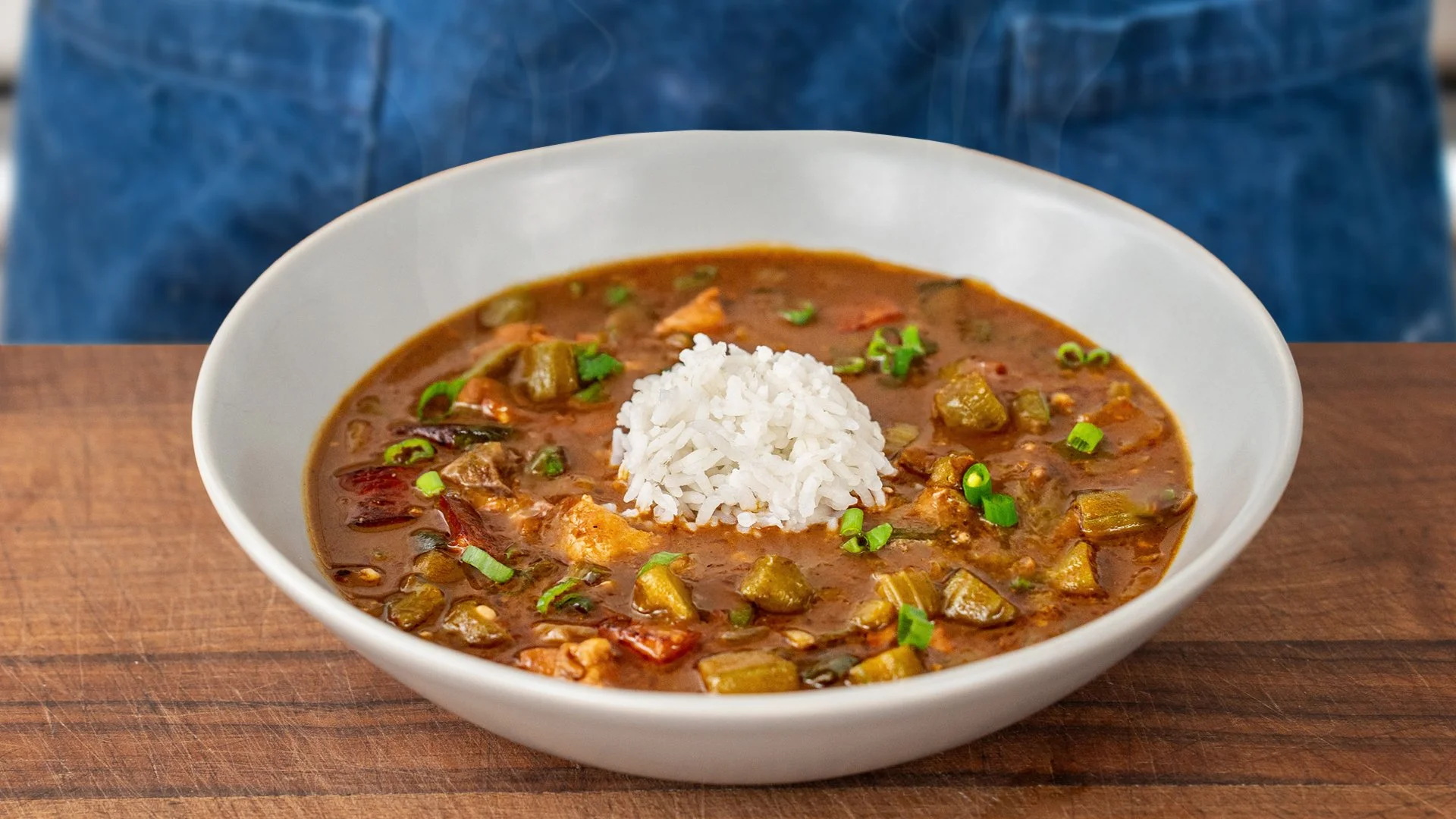 cajun gumbo in a white bowl with a scoop of rice