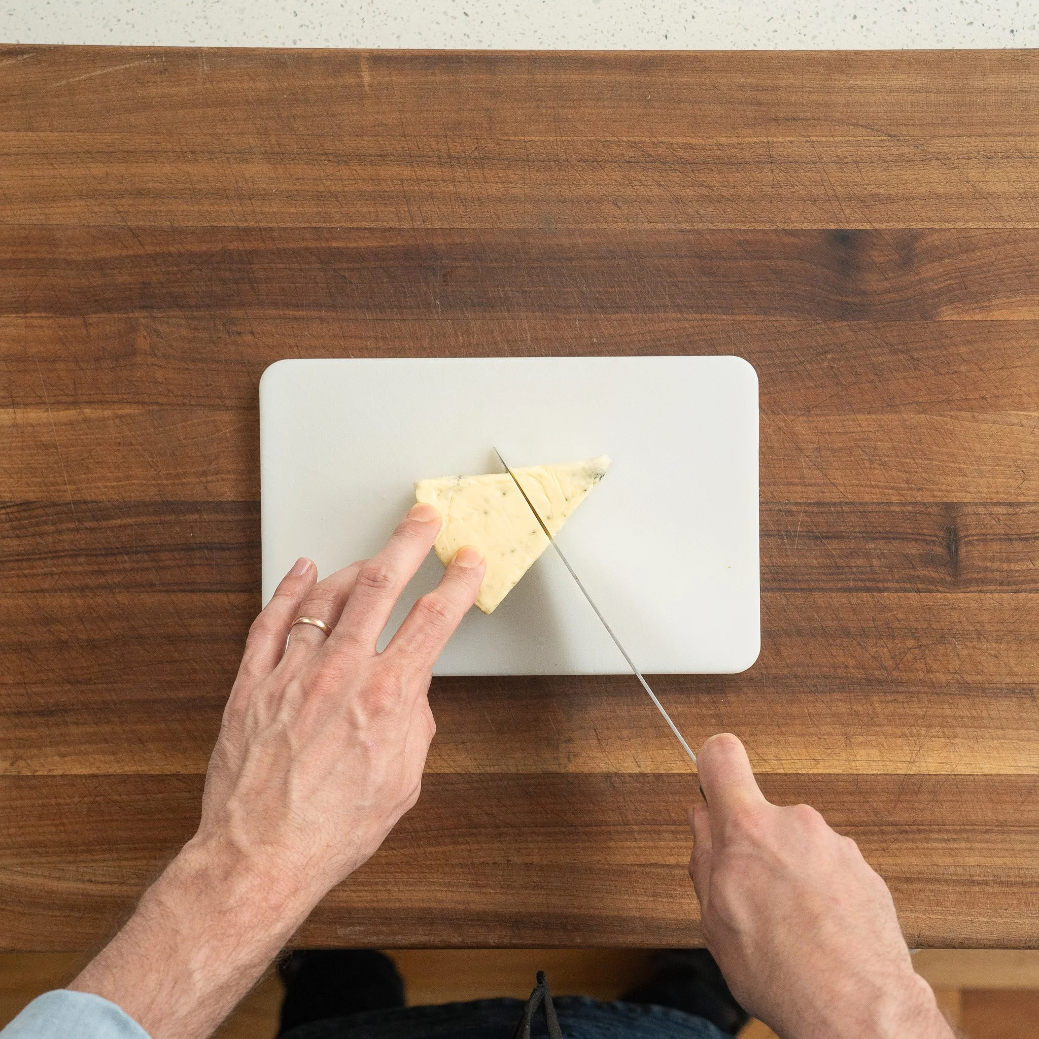 cutting block of blue cheese on a wooden cutting board