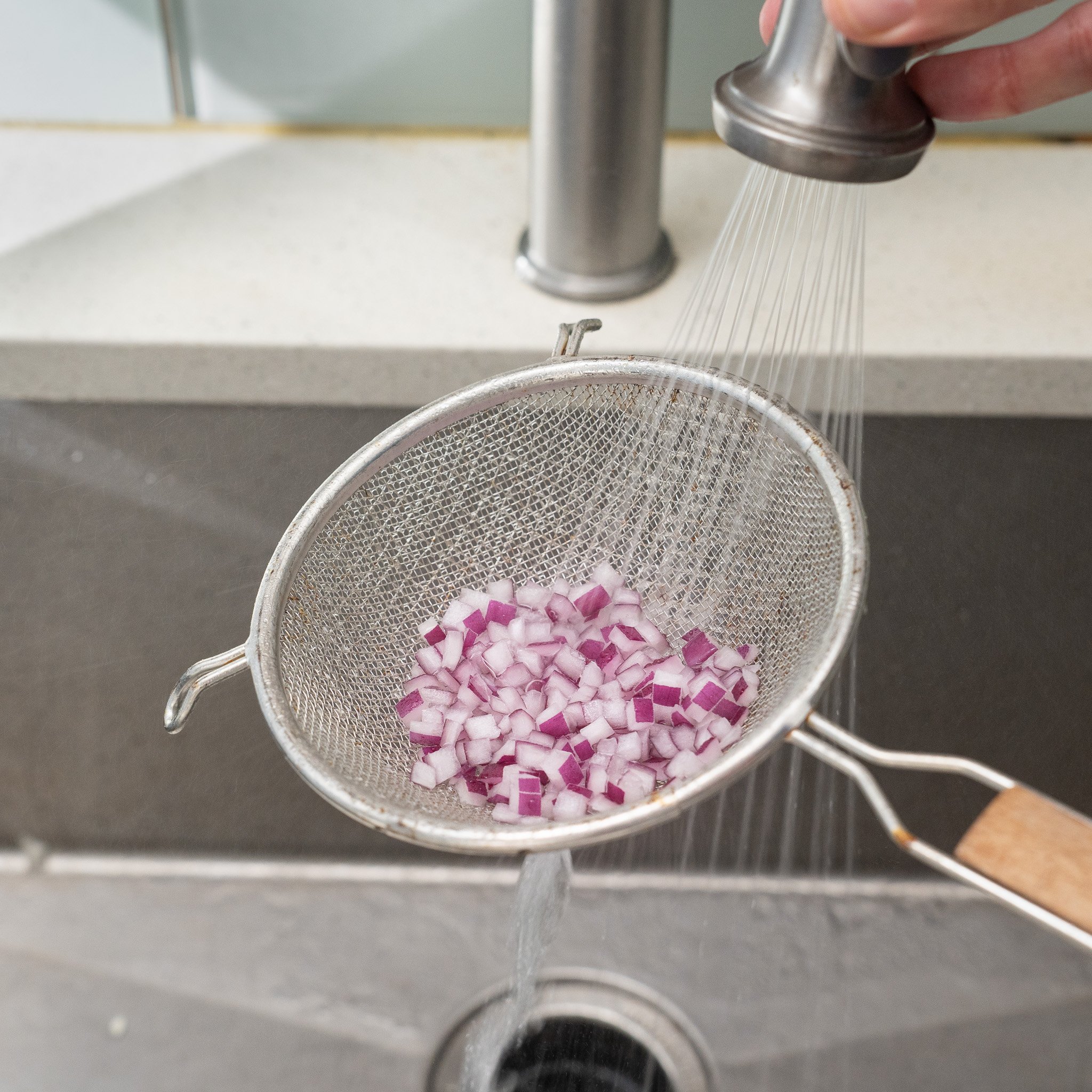 rinsing diced red onions in a strainer with water