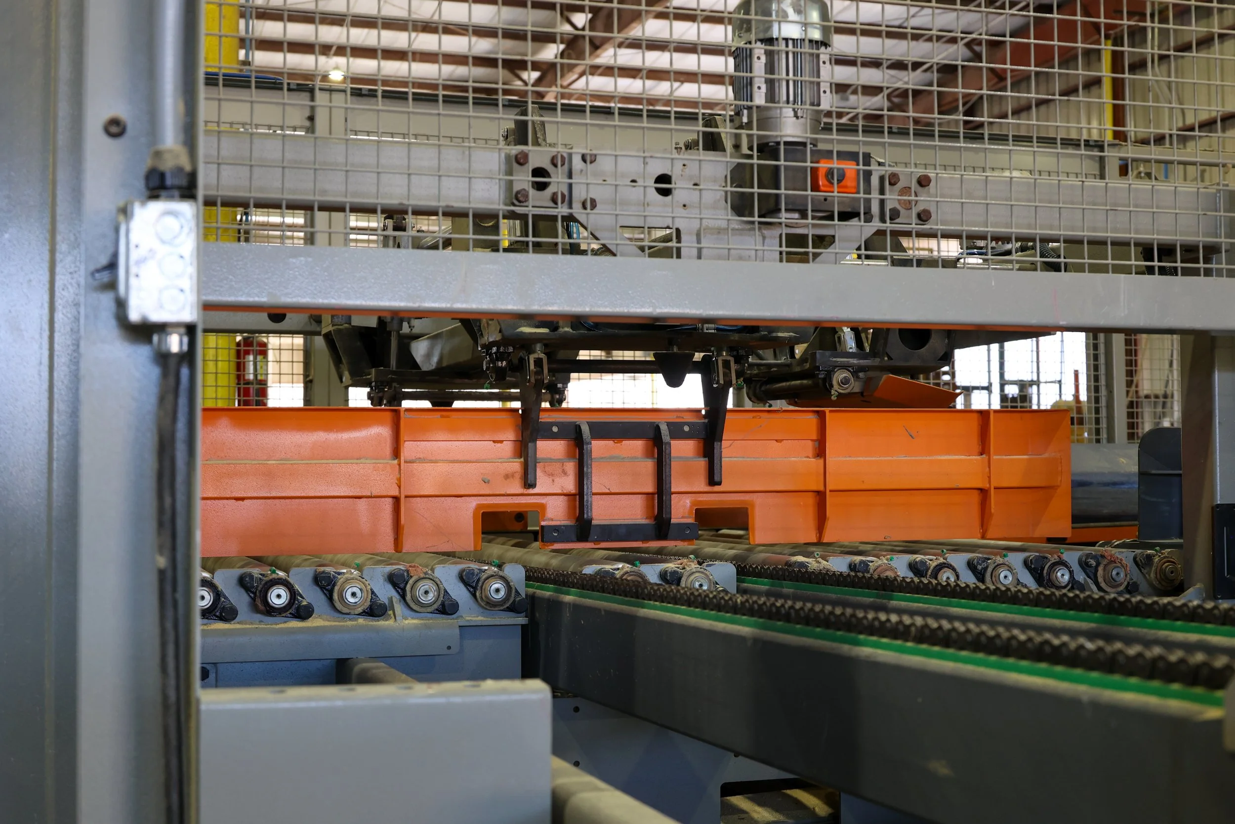 Close-up of industrial machinery with rollers, belts, and metal framing in a manufacturing setting.