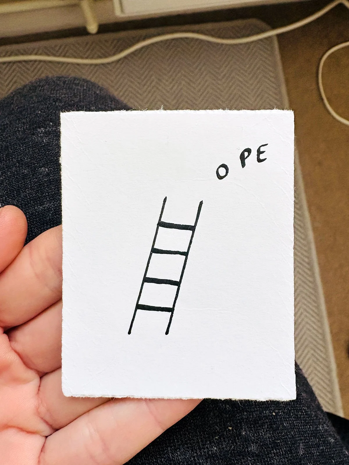 Hope ink drawing. A small white piece of paper with a black ladder drawn on it and the words "OPE" written above the ladder's top rung which looks like an "H". 