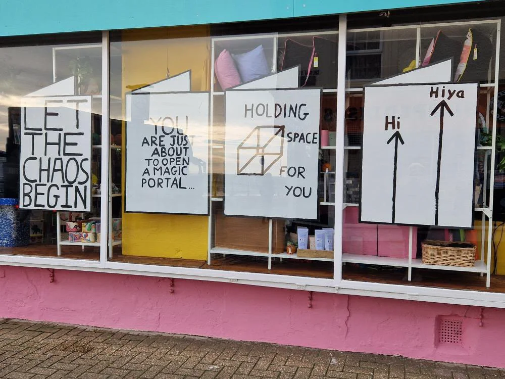 Neighbourhood Store Shop Windows featuring giant plywood cards that read "Let the chaos begin" etc