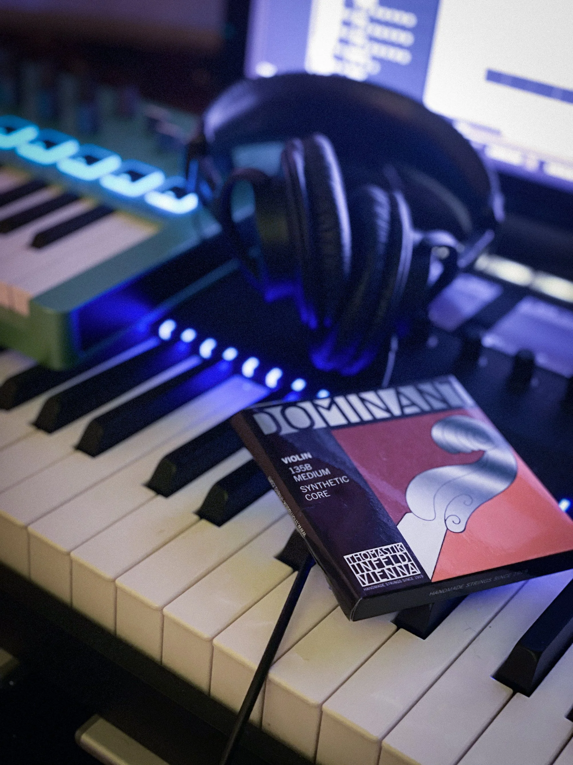 Violin strings and headphones resting on a keyboard in a recording studio