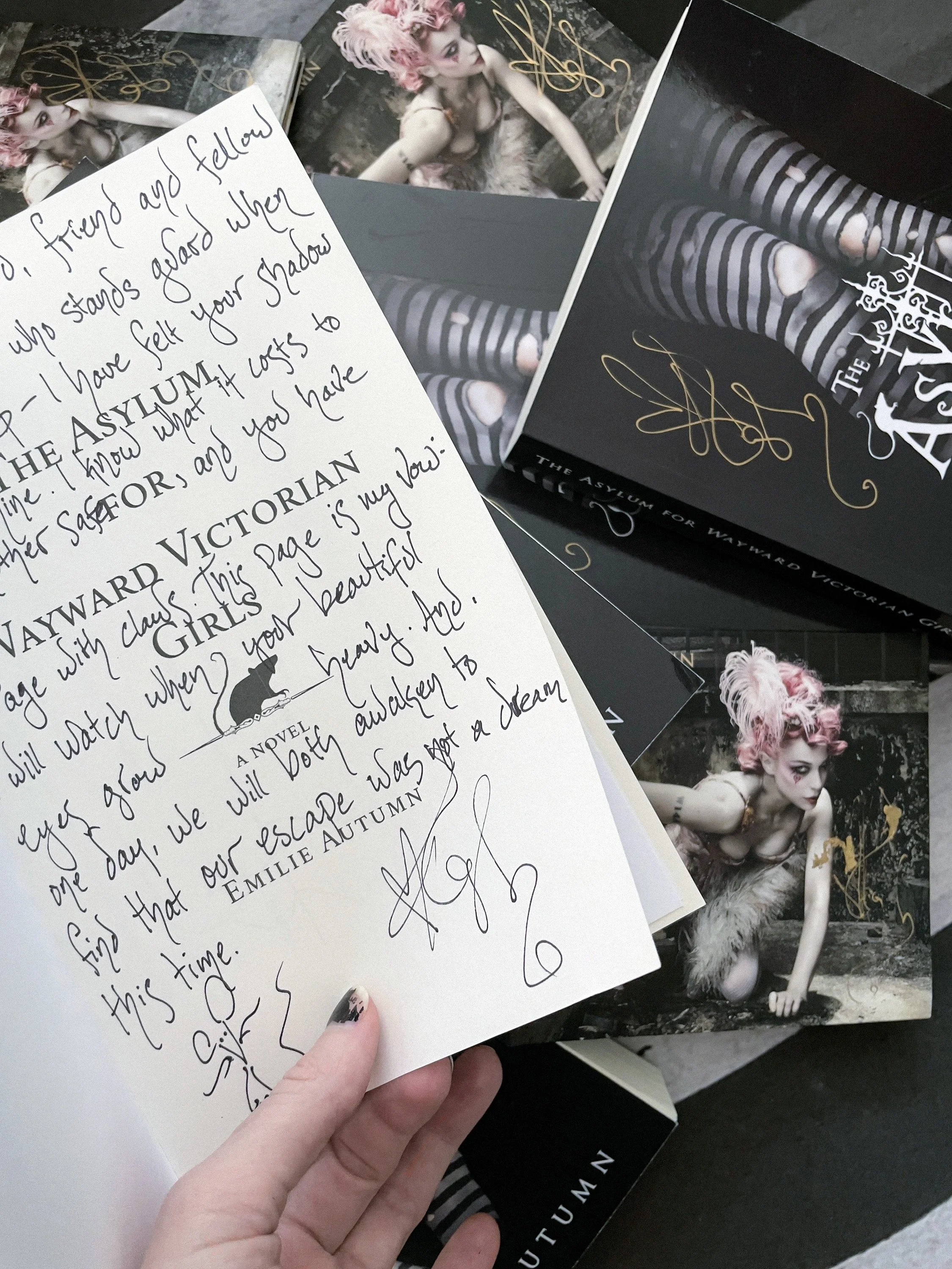 Handwritten dedication inside “The Asylum for Wayward Victorian Girls,” held in hand beside signed album cards.