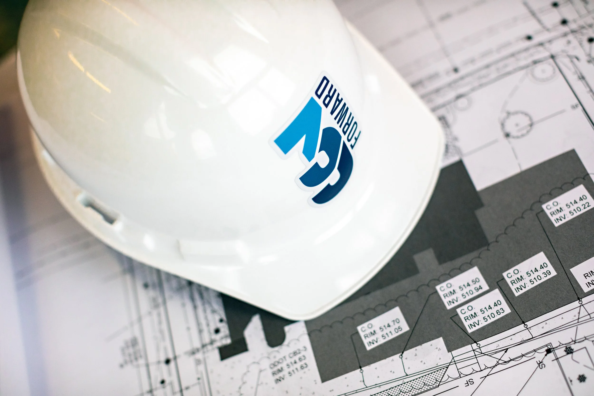 Photo of construction hat with 39Forward logo, floor plans.