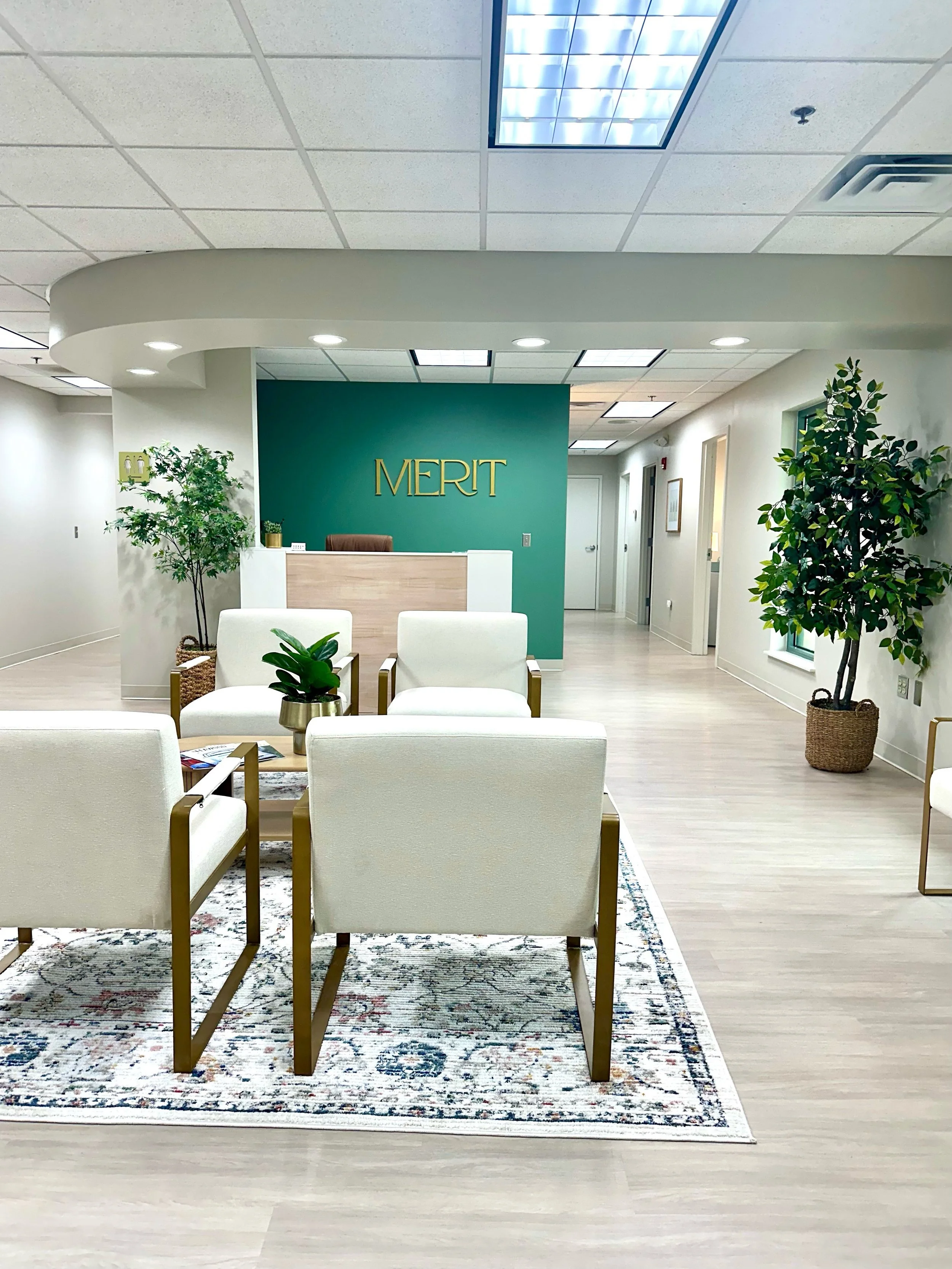 The well lit & beautifully decorated Merit KC lobby/waiting room with a green accent wall with MERIT in gold lettering