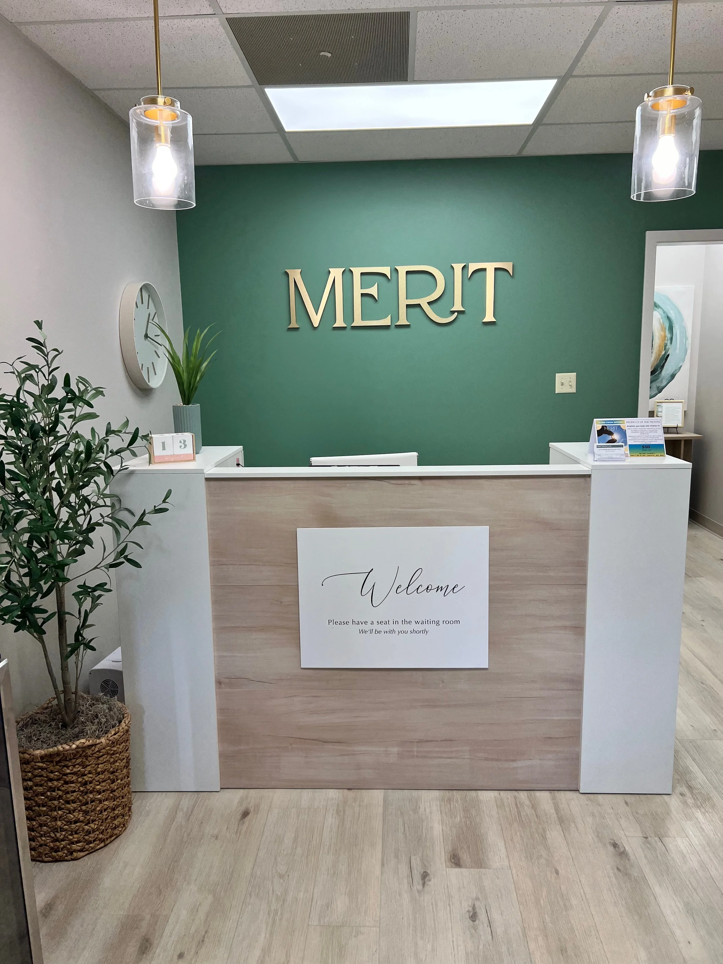 The Merit Topeka front desk with a welcome sign and a green accent wall with MERIT in gold lettering