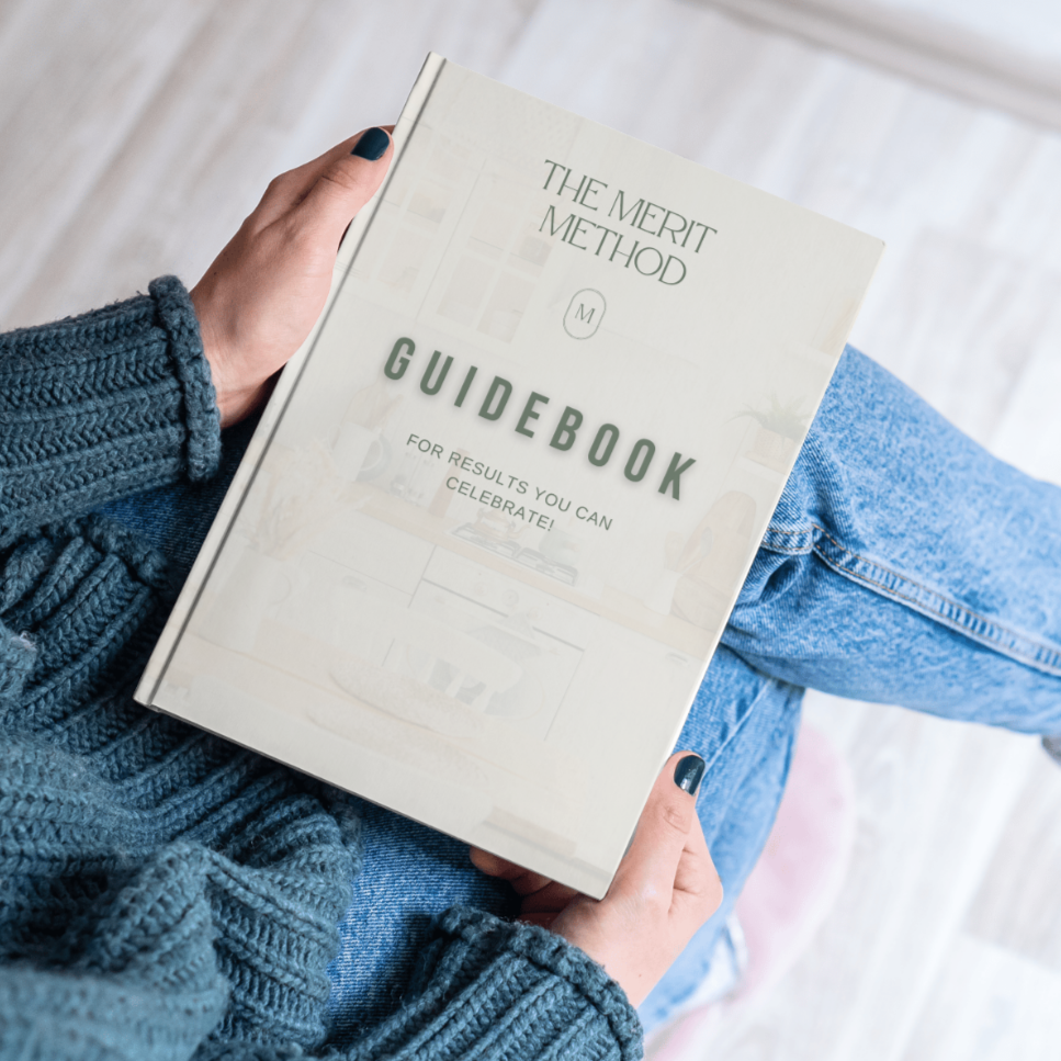 The Merit Method Guidebook in the hands of a woman sitting down in jeans