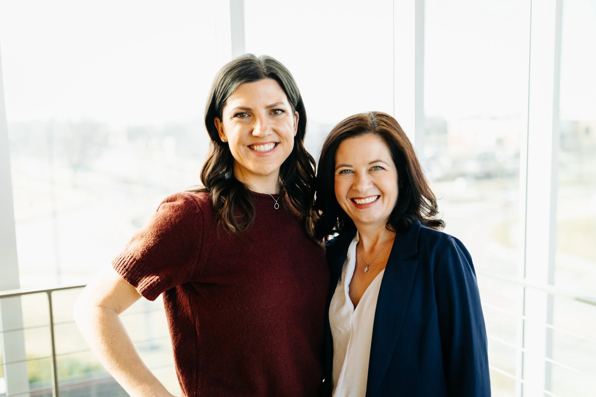Merit owners stephanie and veronica stand in front of a window smiling