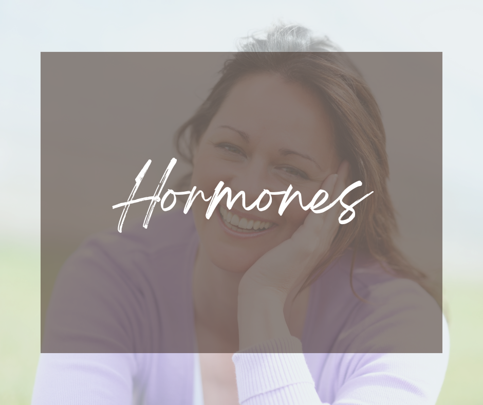 A woman smiling with her hand on her face with "hormones" overlaid on the top.