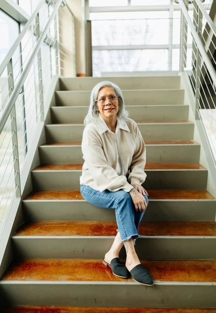 Merit Topeka's MA, Elizabeth, sits on stairs with legs crossed smiling