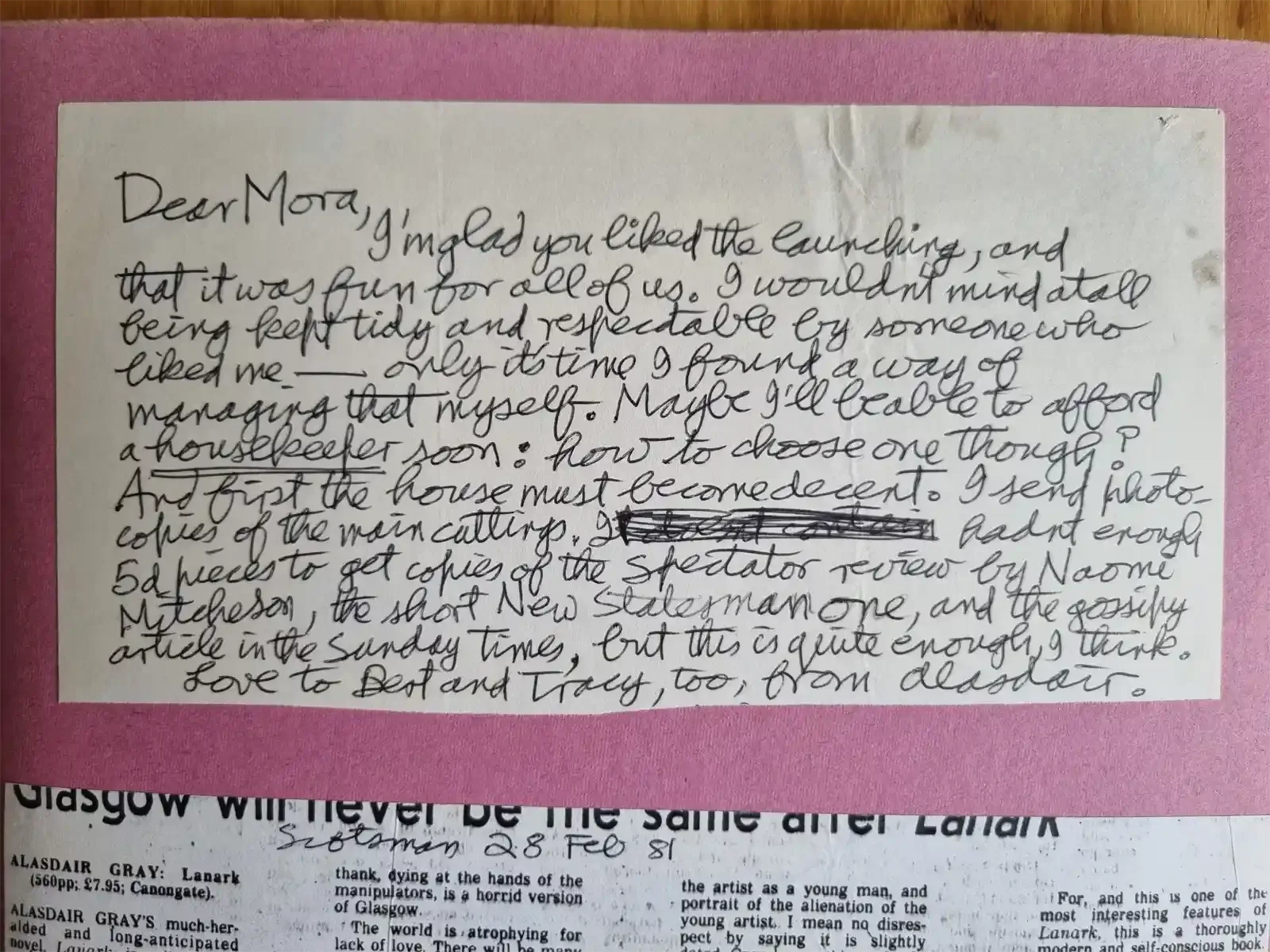 A handwritten letter on a pink scrapbook page beginning 'Dear Mora'. Below it, part of a newspaper review headlined 'Glasgow will never be the same after Lanark'.