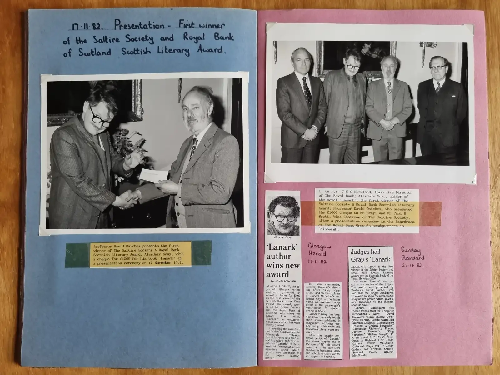 Two scrapbook pages, one blue and one pink, with black and white photographs of an award ceremony: Alasdair shaking hands and receiving an envelope and four men in suits posed together.