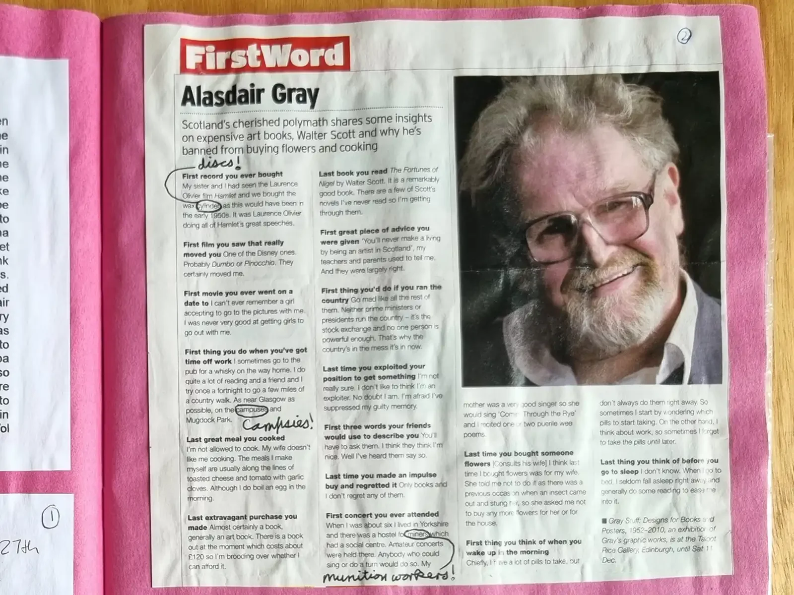 A newspaper interview headed 'First Word: Alasdair Gray' on a pink scrapbook page, with a photograph of Alasdair smiling. Three printed words are circled and corrected by hand.
