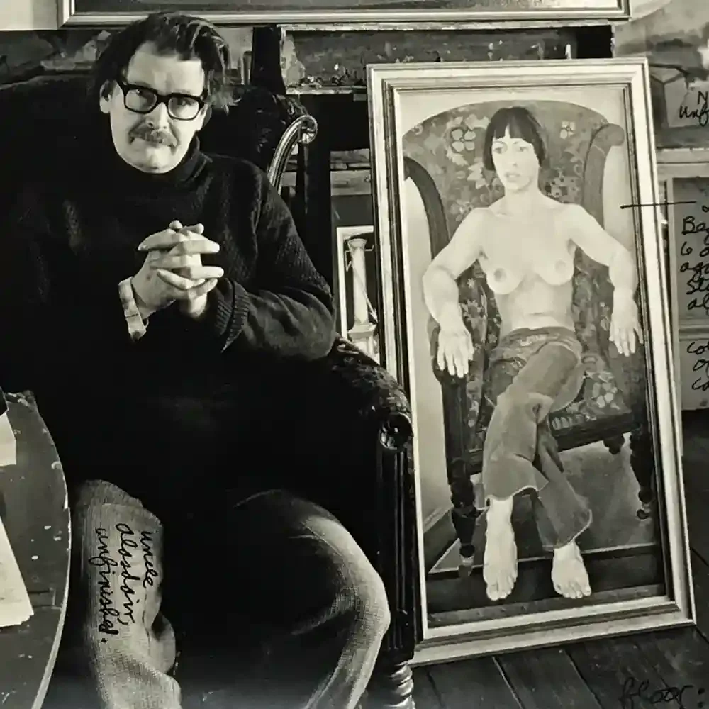Middle aged white man with clasped hands, untidy hair and glasses looks at us seriously. He's sitting in a big chair next to a painting of a strong woman naked from the waist in the same chair. Writing on his leg says Uncle Alasdair Unfinished.