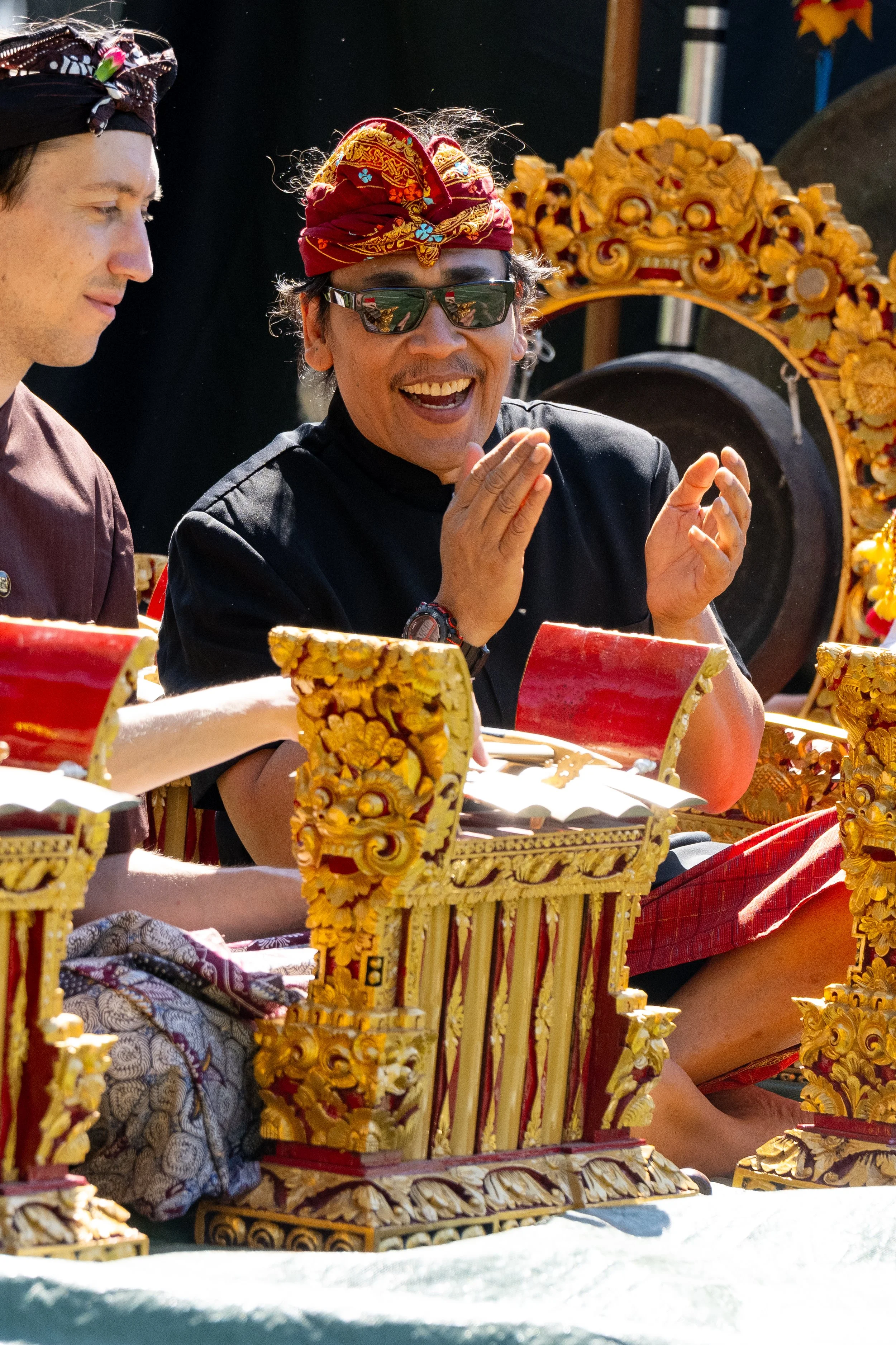 Person wearing a patterned headscarf and ornate costume, holding a tambourine.