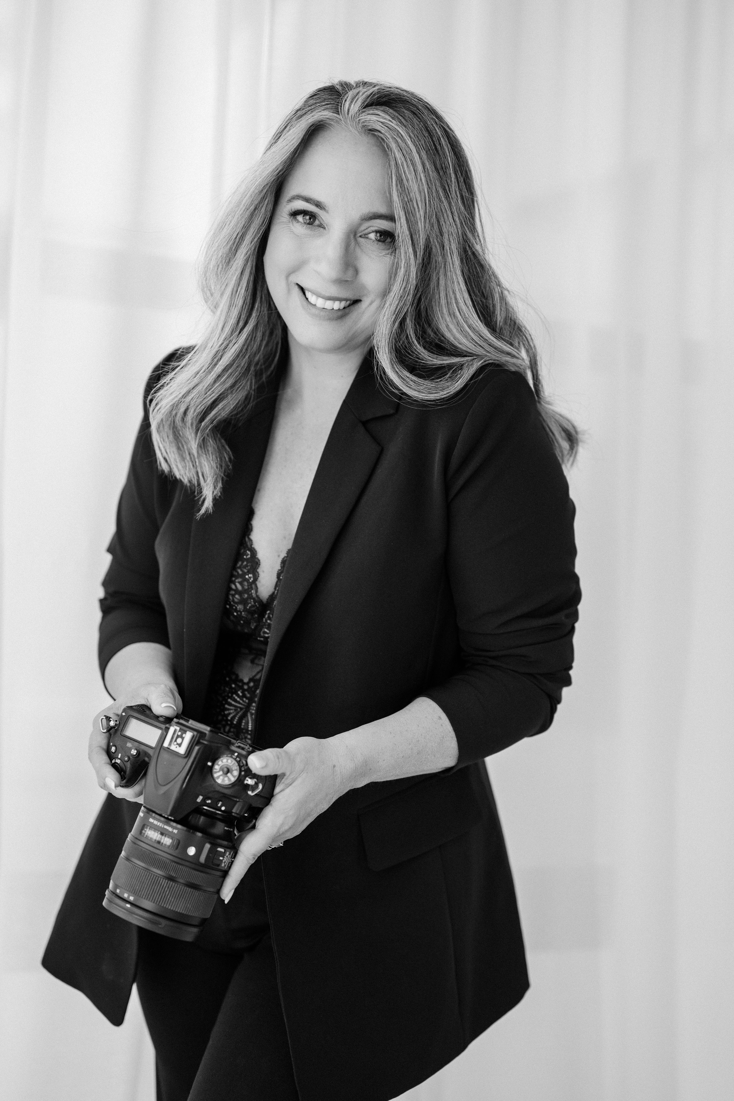 Diana, portrait photographer and owner of Depiction Portraits, holding her camera in her Woodstock, Virginia studio