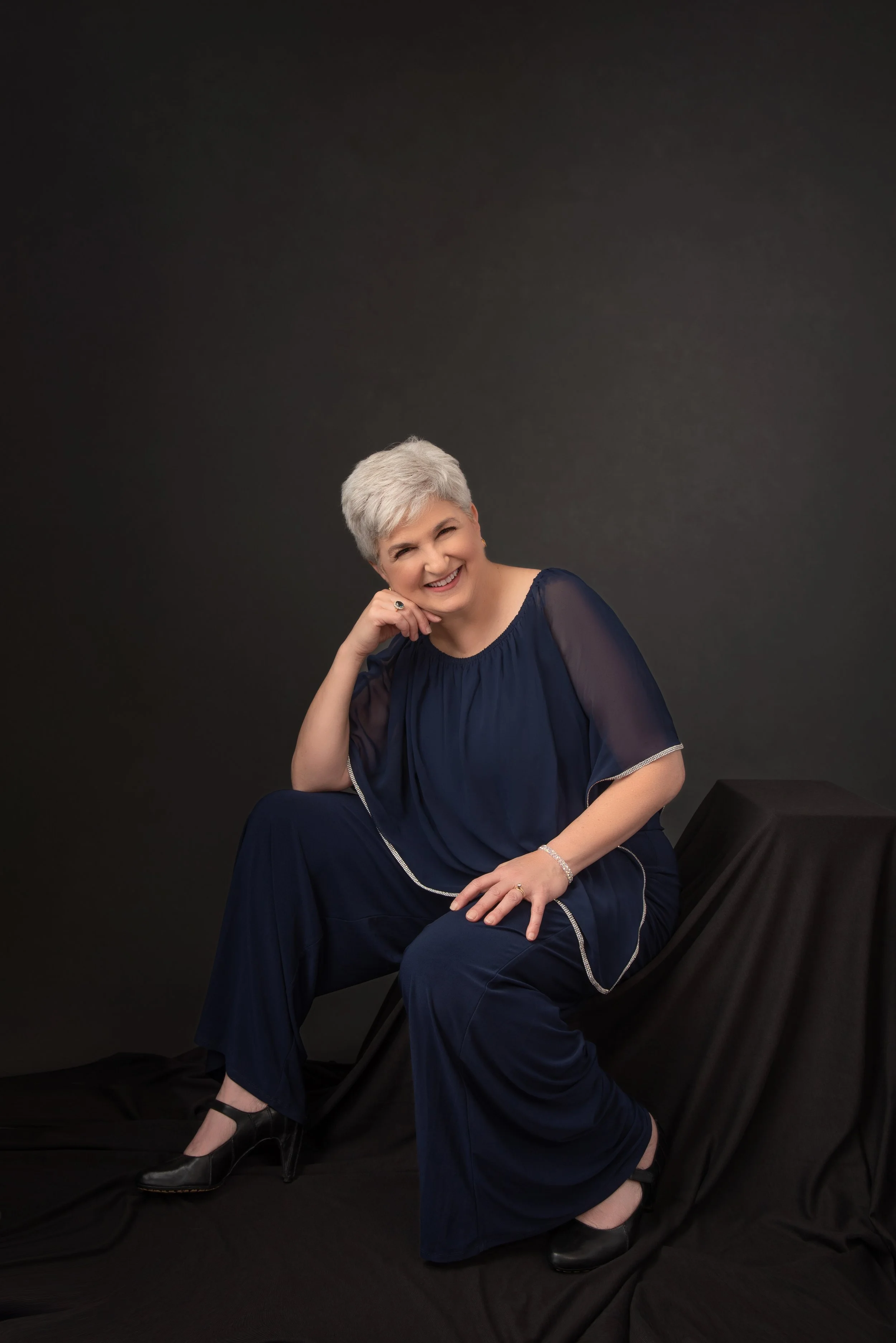 Elegant studio portrait of an older woman in a flowing blue outfit, smiling at the camera, photographed by Depiction Portraits in Woodstock, Virginia