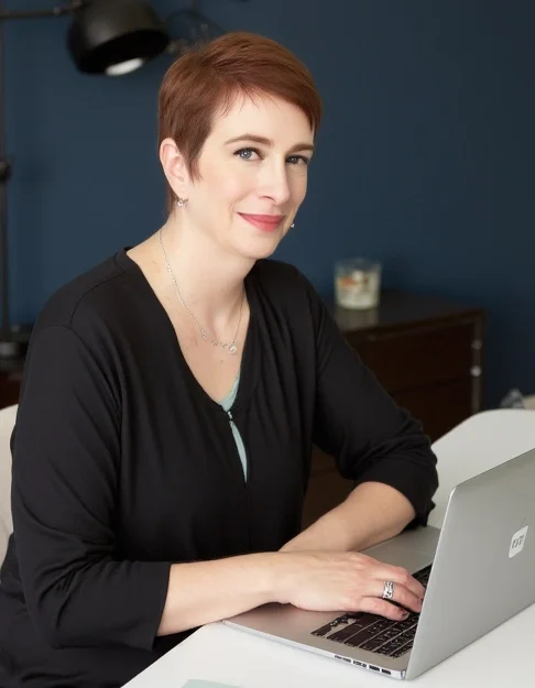 Meg Desjarlais sitting at her desk with her laptop working on her blog