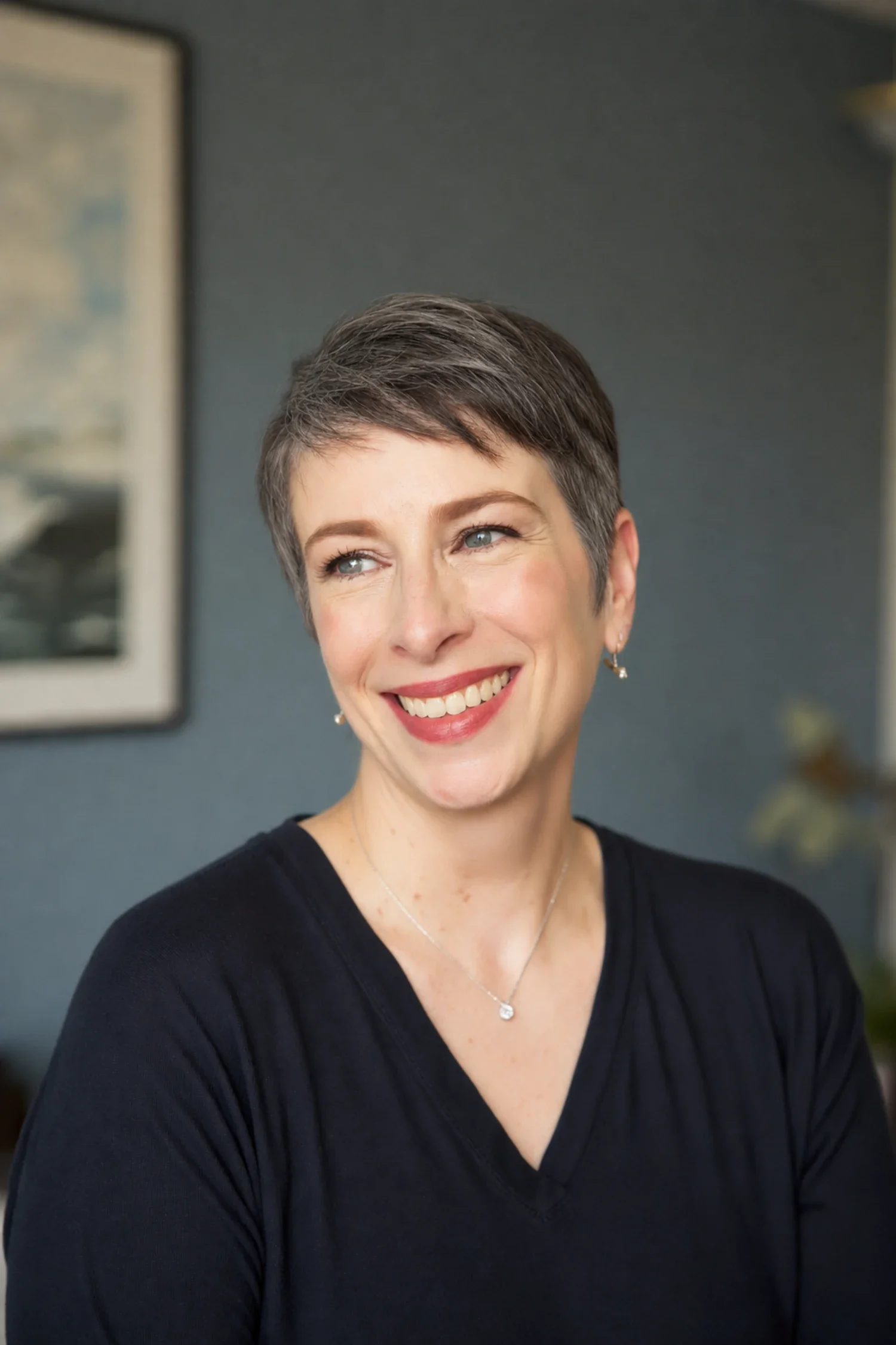 Meg Desjarlais smiling warmly in a navy top with a slate wall behind her.
