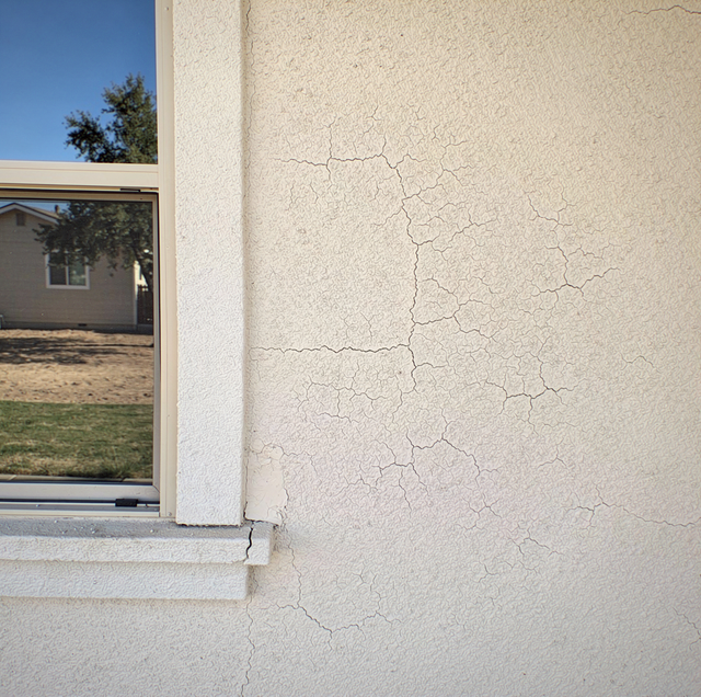 Hairline cracks branching across dry stucco wall exterior