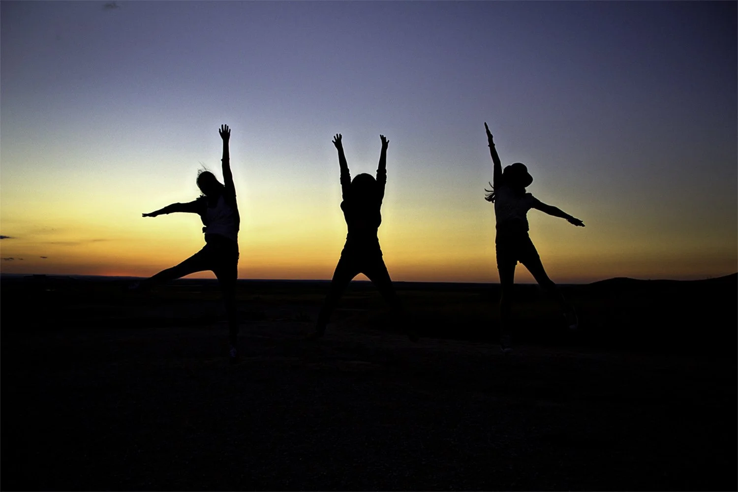 Three silhouettes of females jumping at sunset. Badlands National Park South Dakota. 