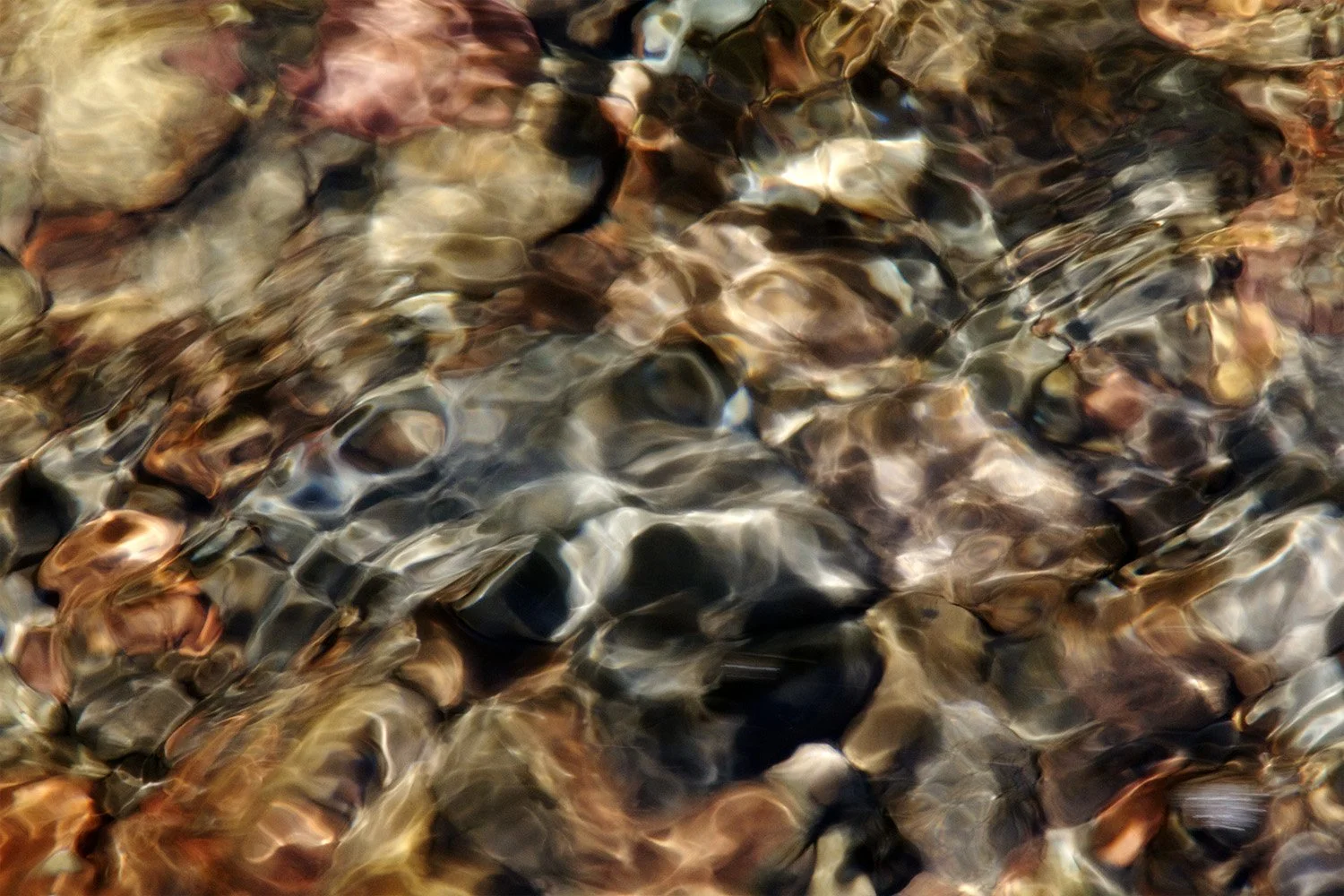 Close up of river with colorful rocks below. Gallatin River in Bozeman Montana.