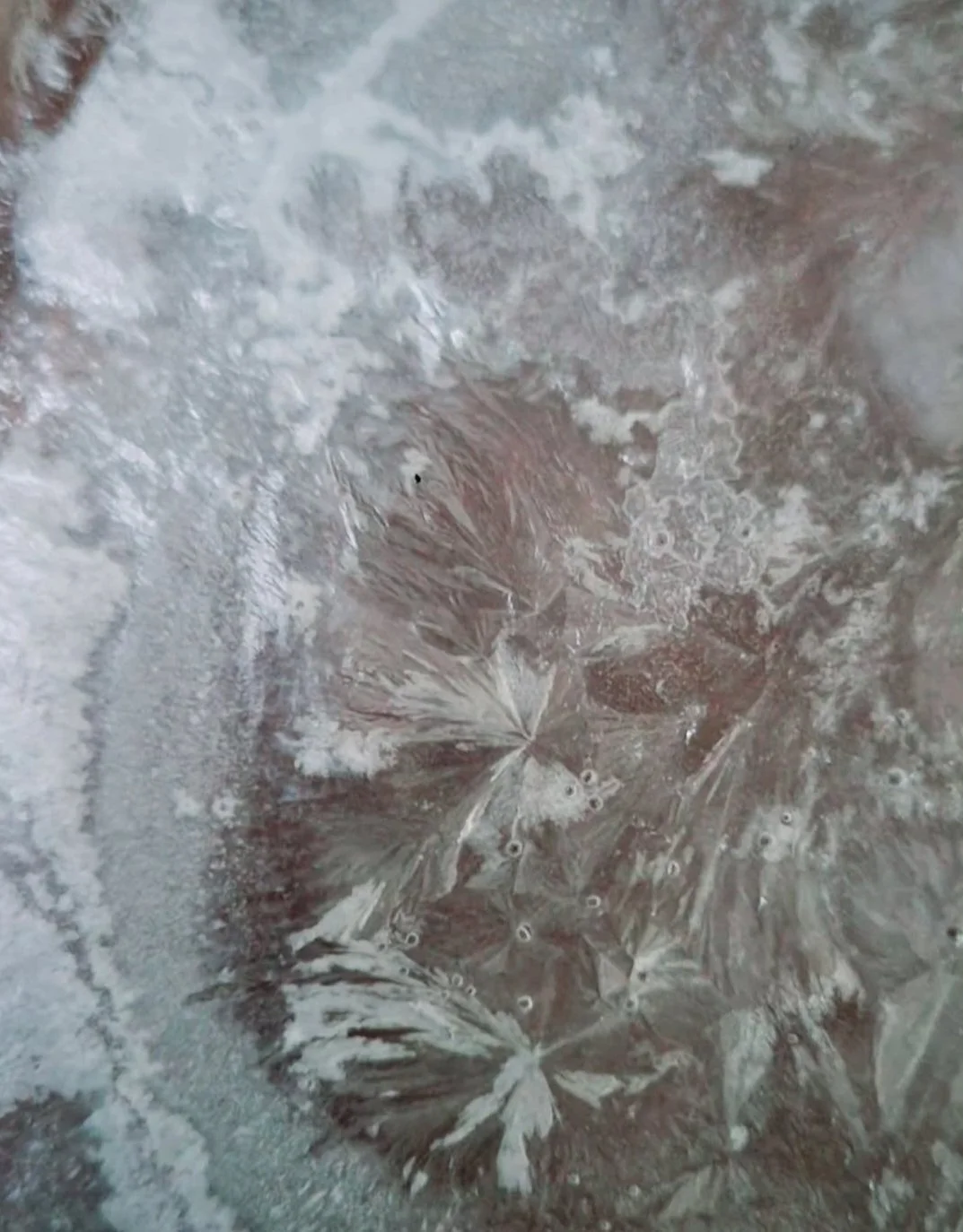 Frozen ice with intricate frost patterns and bubbles.
