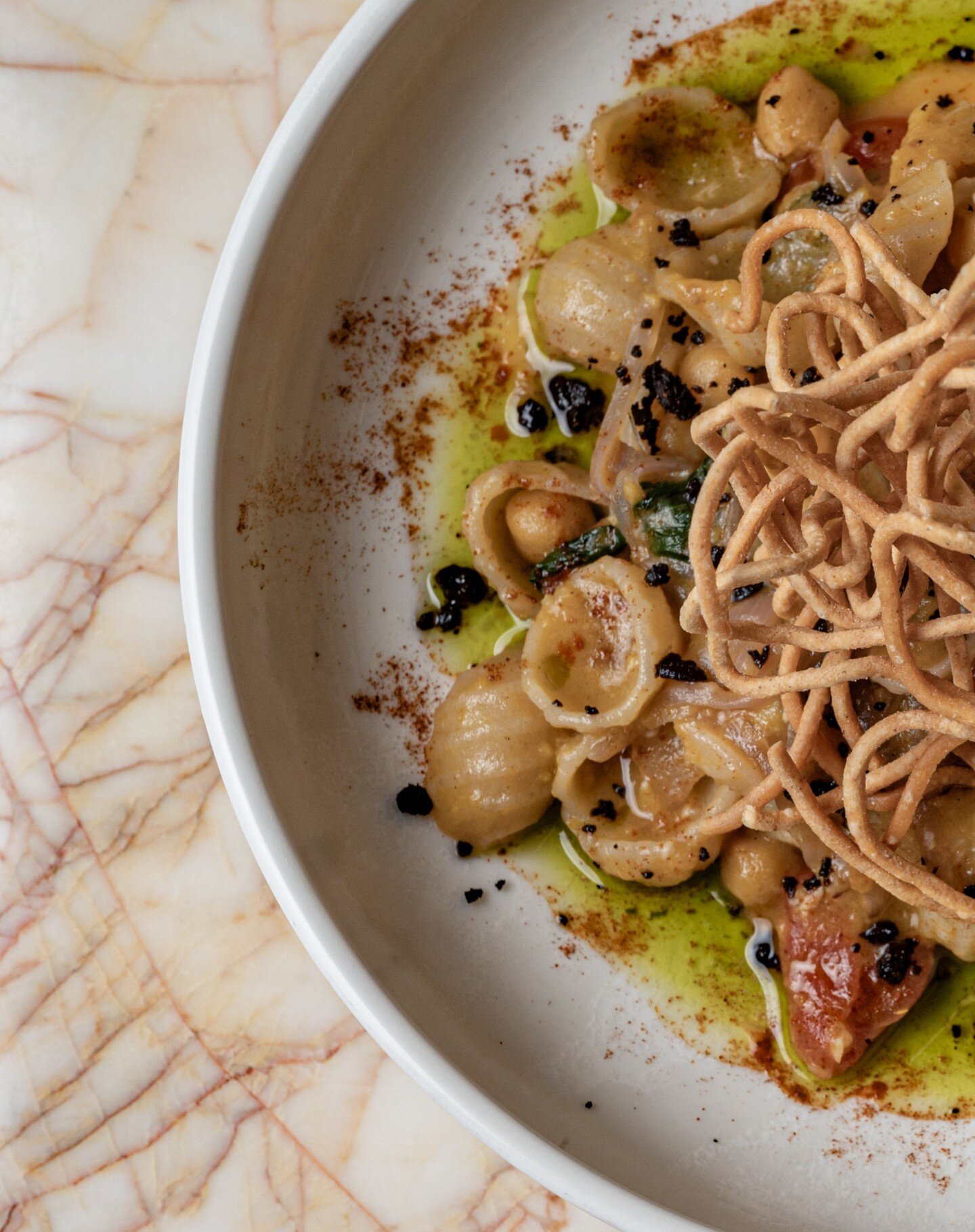 Orecchiette are a pasta typical of Apulia, a region of Southern Italy. Their name comes from the direct translation of 'little ears.' 
Ours is served with guanciale (pork cheek,) chilli, dried olives, basil oil and some crispy pasta for added texture