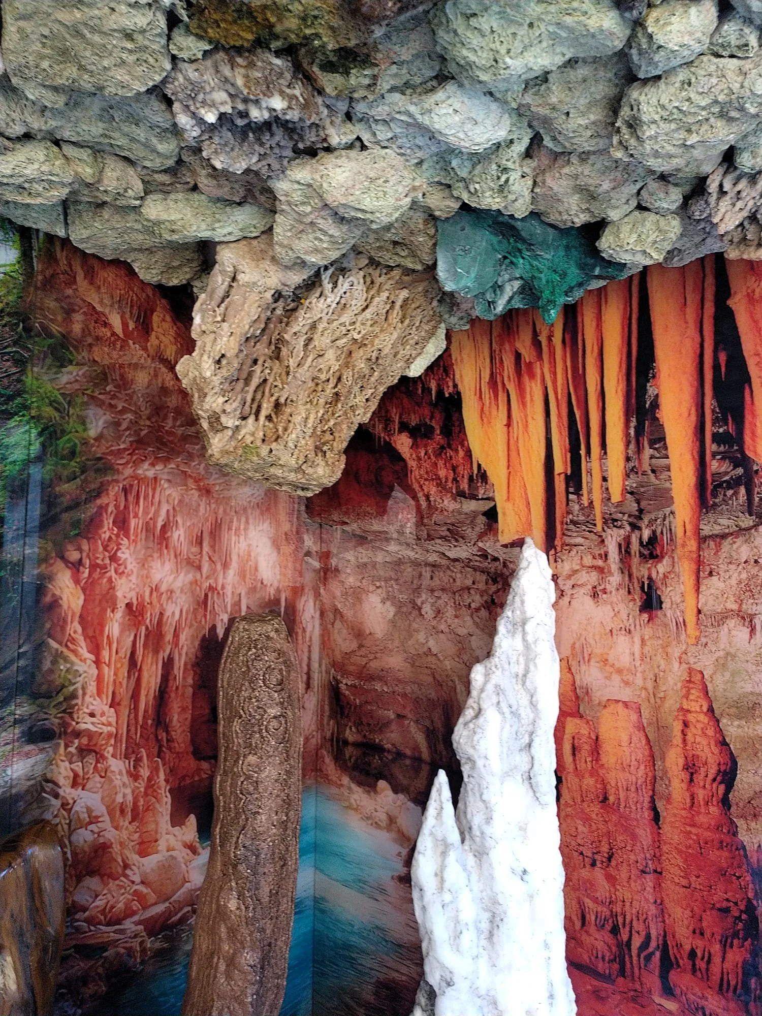 Una representación artística de una caverna con estalactitas y estalactitas en colores rojos, anaranjados, blancos y verdes.