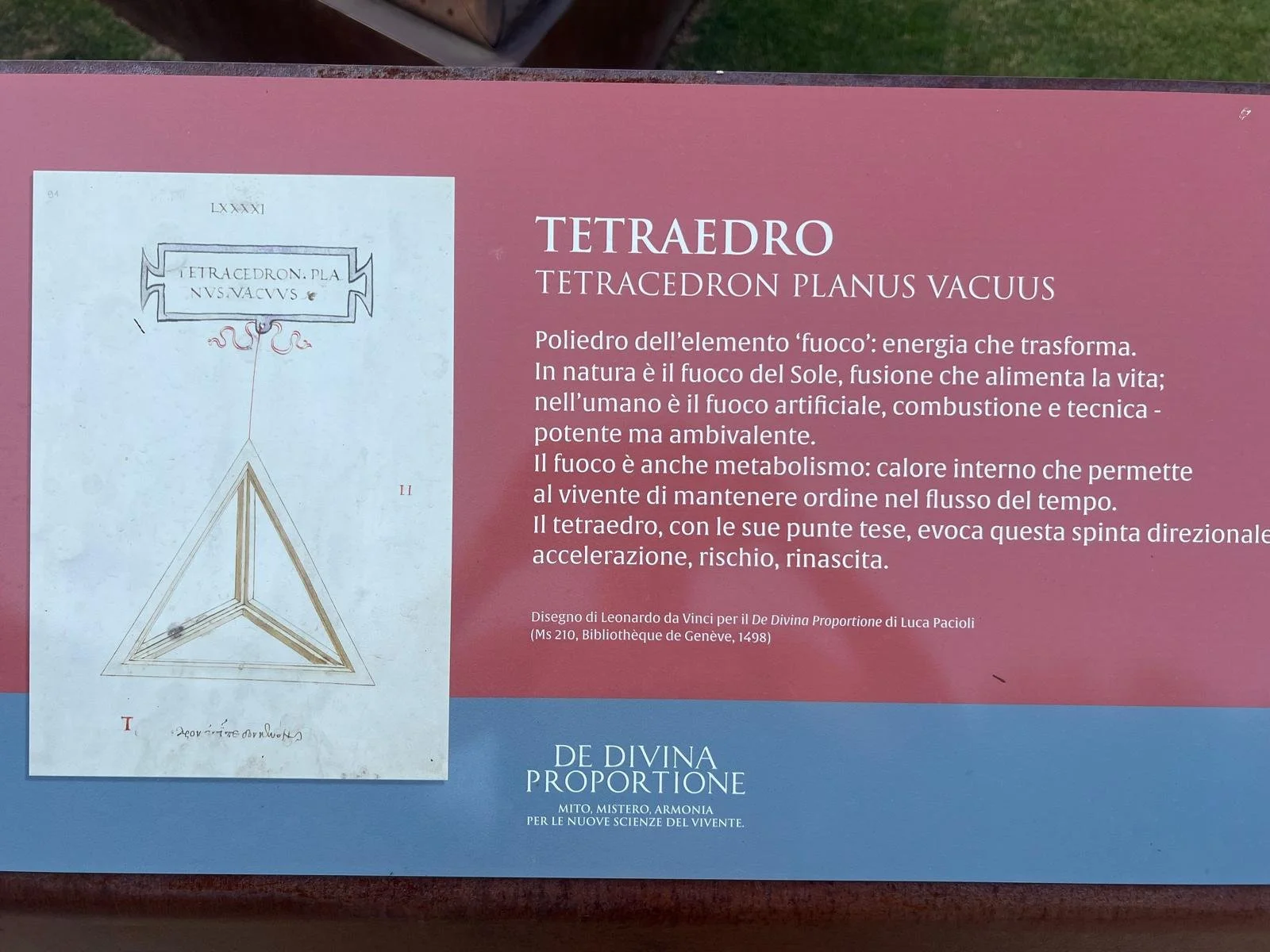 Cartel explicativo sobre el tetraedro, su relación con el elemento fuego y su simbolismo en la energía y el metabolismo, con una ilustración del tetraedro y texto en italiano y español.
