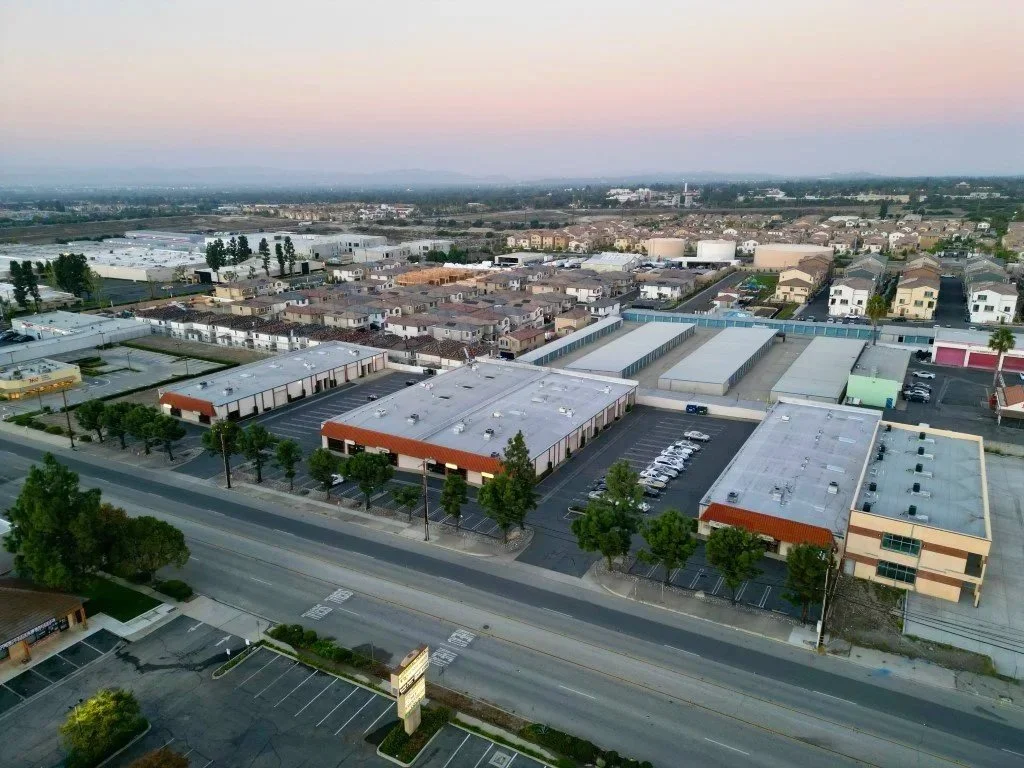 An aerial view of an industrial park with parking by residential houses at sunrise.