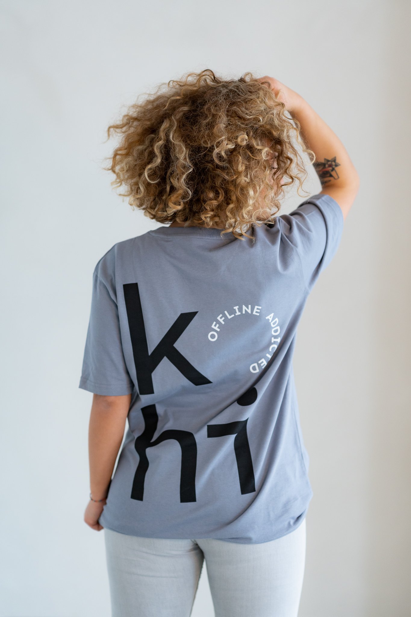 Weibliches Model trägt blaugraues Tshirt mit großem kohi-Print mit offline-addicted-Stempel auf dem Rücken.