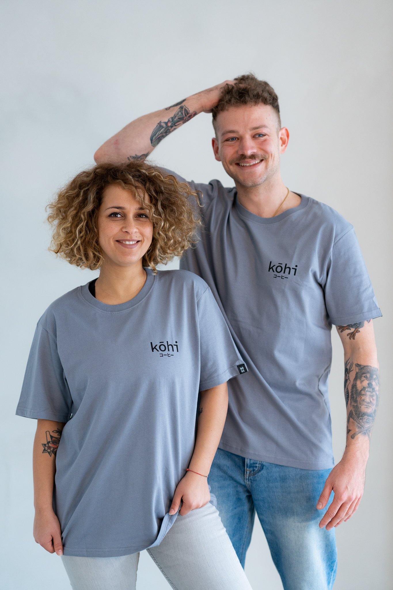Paar trägt blaugraue Tshirts mit kohi-Logo auf der Brust.