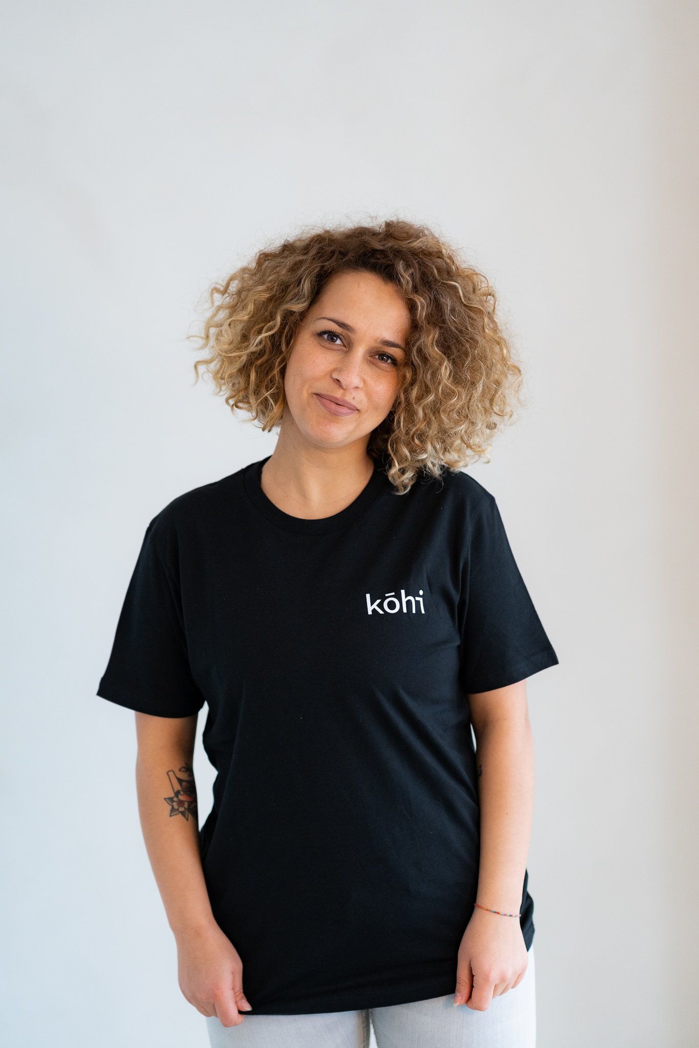 Weibliches Model trägt schwarzes Tshirt mit kohi-Logo auf der Brust.